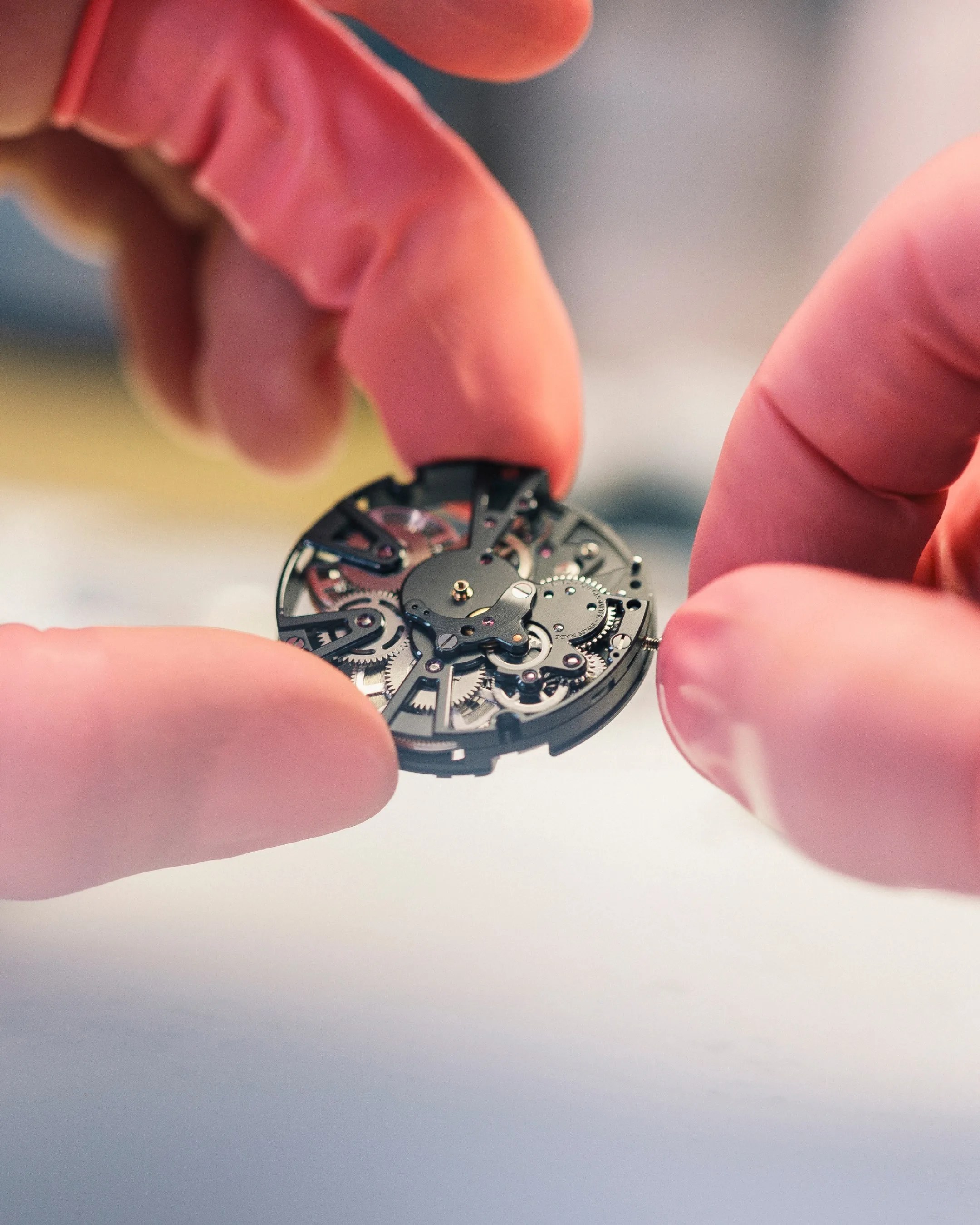 fingers holding a christopher ward automatic watch movement