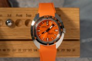 orange doxa dive watch on a wooden board
