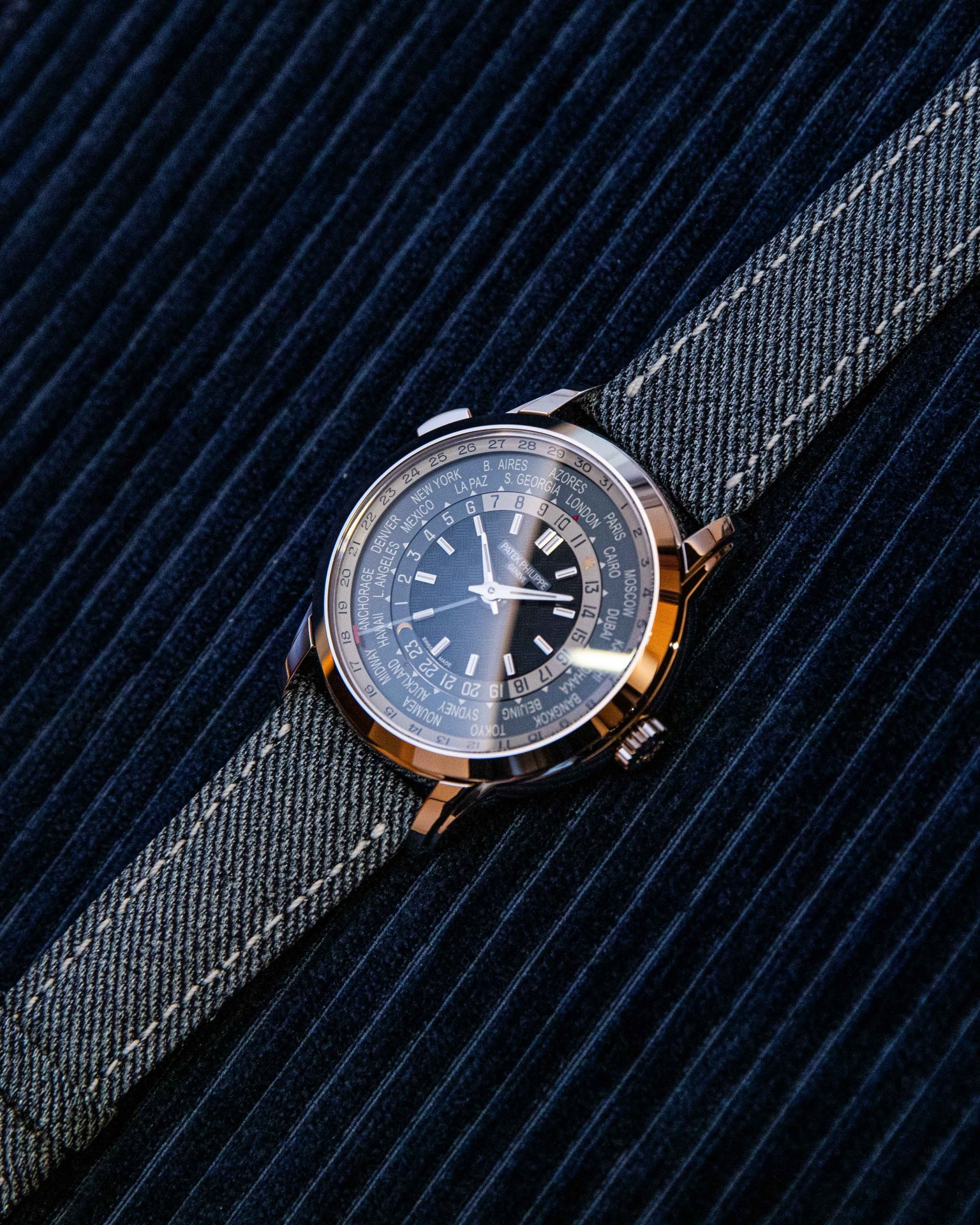 The Patek Philippe ref. 5980/60G shown resting flat against a pinstriped material background