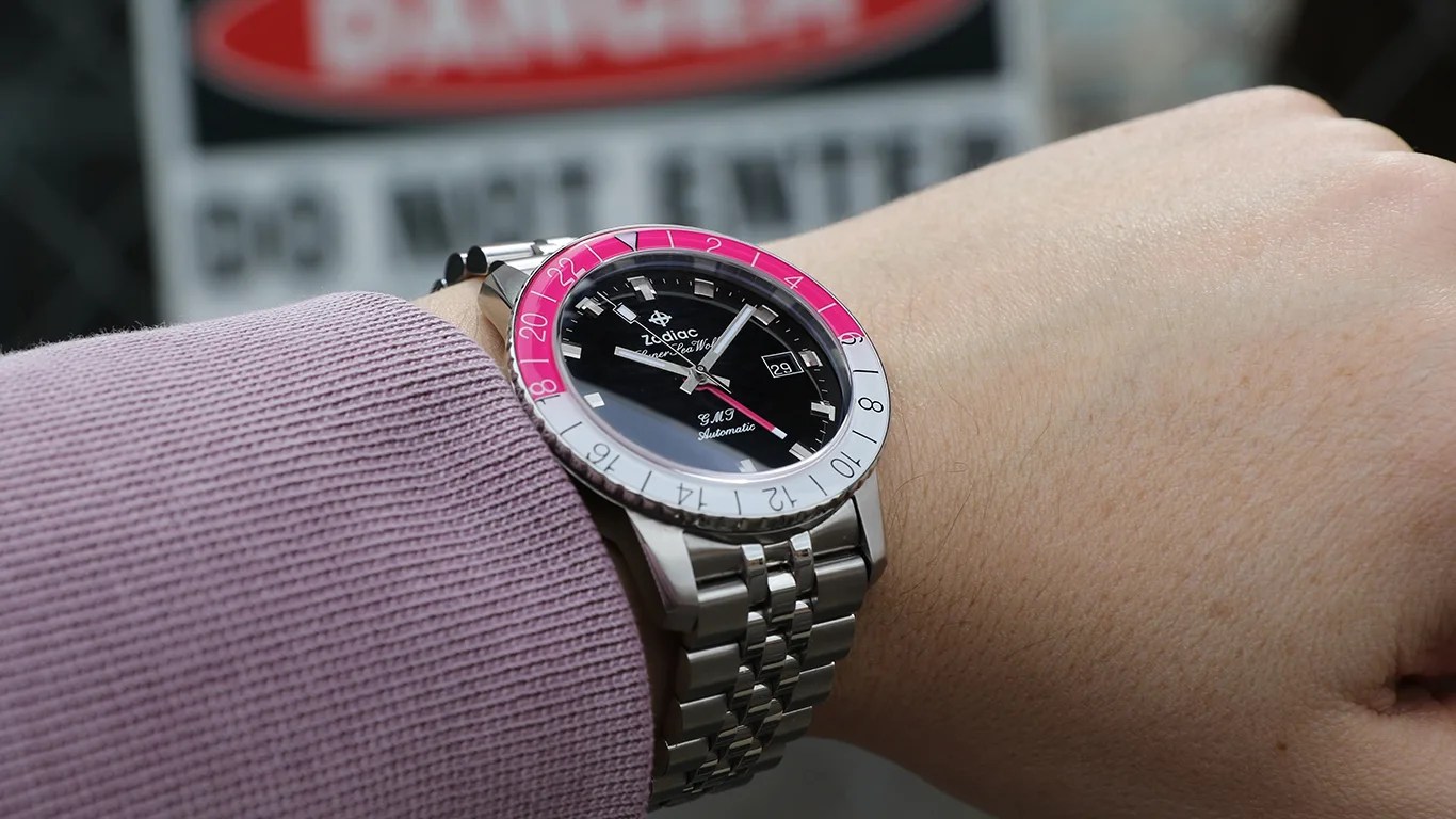 zodiac watch on mans wrist in front of danger sign