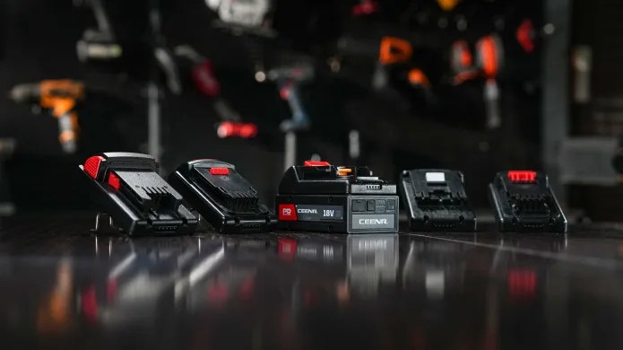 CEENR PDNation powertool battery sitting on polished floor next to four brand battery adaptors. 