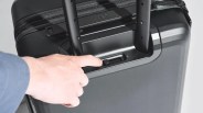 person adjusting a toggle on a black suitcase