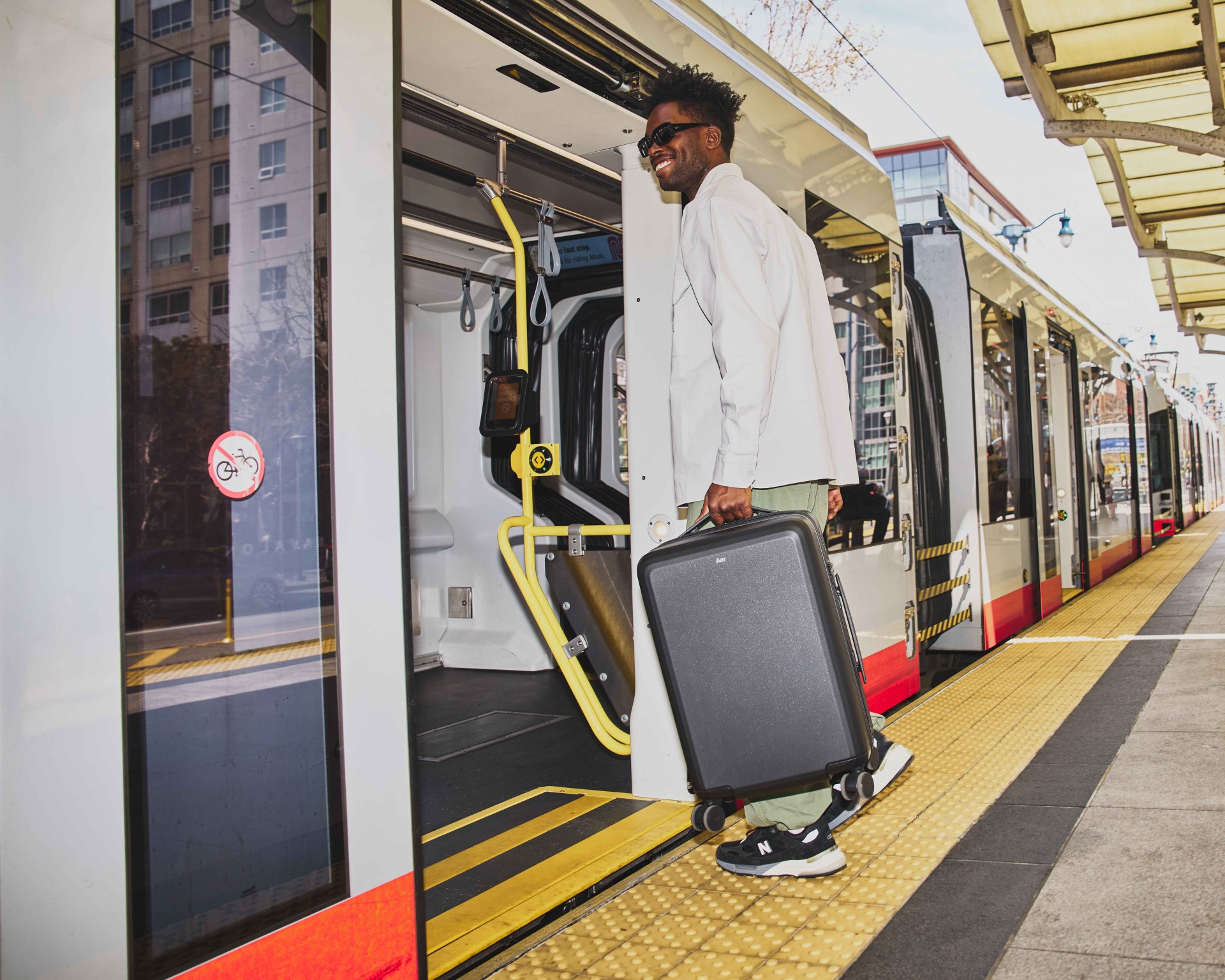 man carrying a suitcase and entering a city train