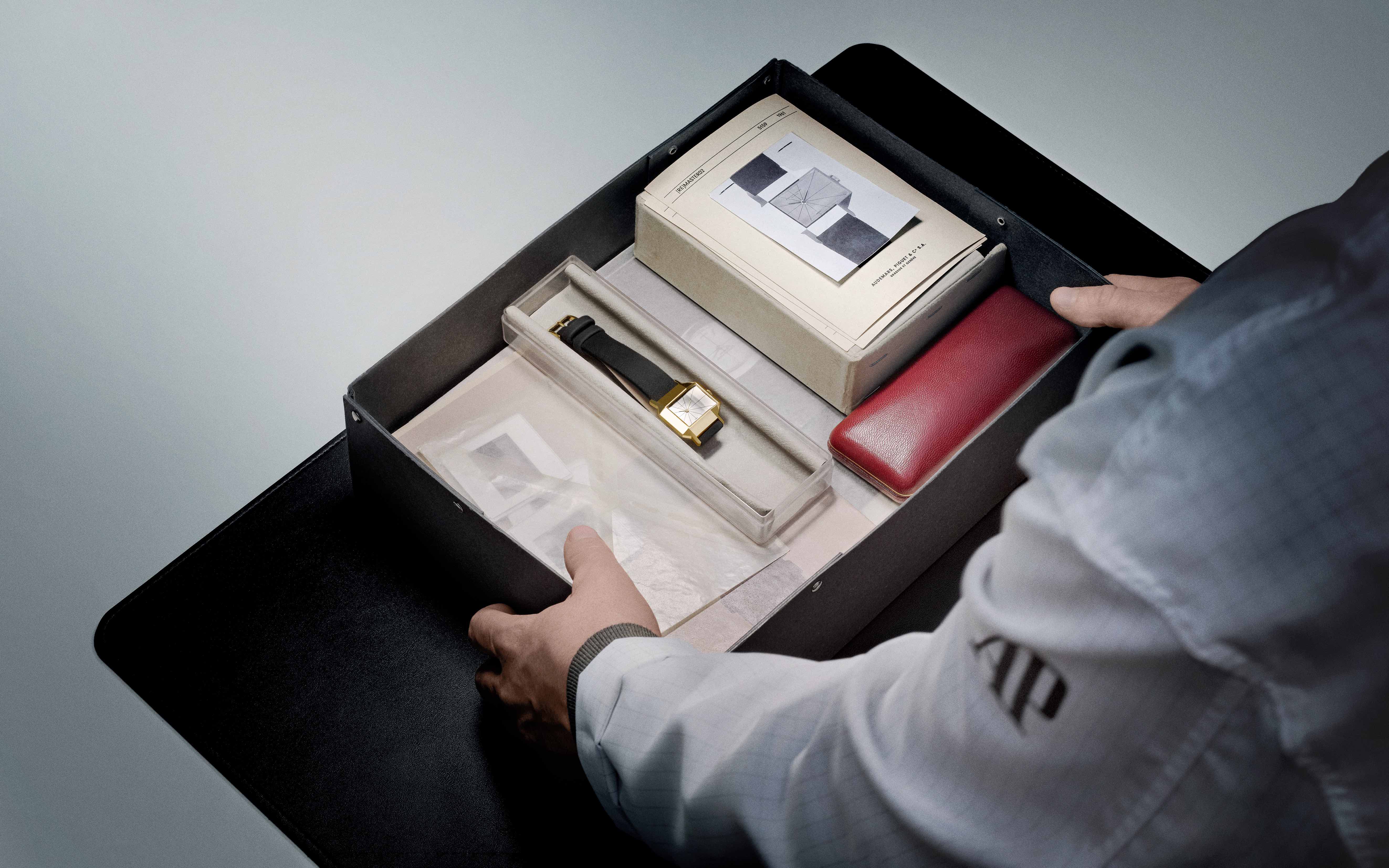 a man looks at a box containing a vintage Audemars Piguet watch