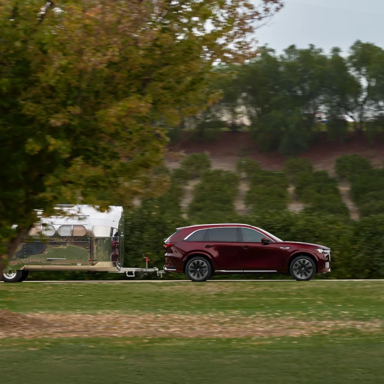 a red Mazda CX-90 pulling a trailer on a field