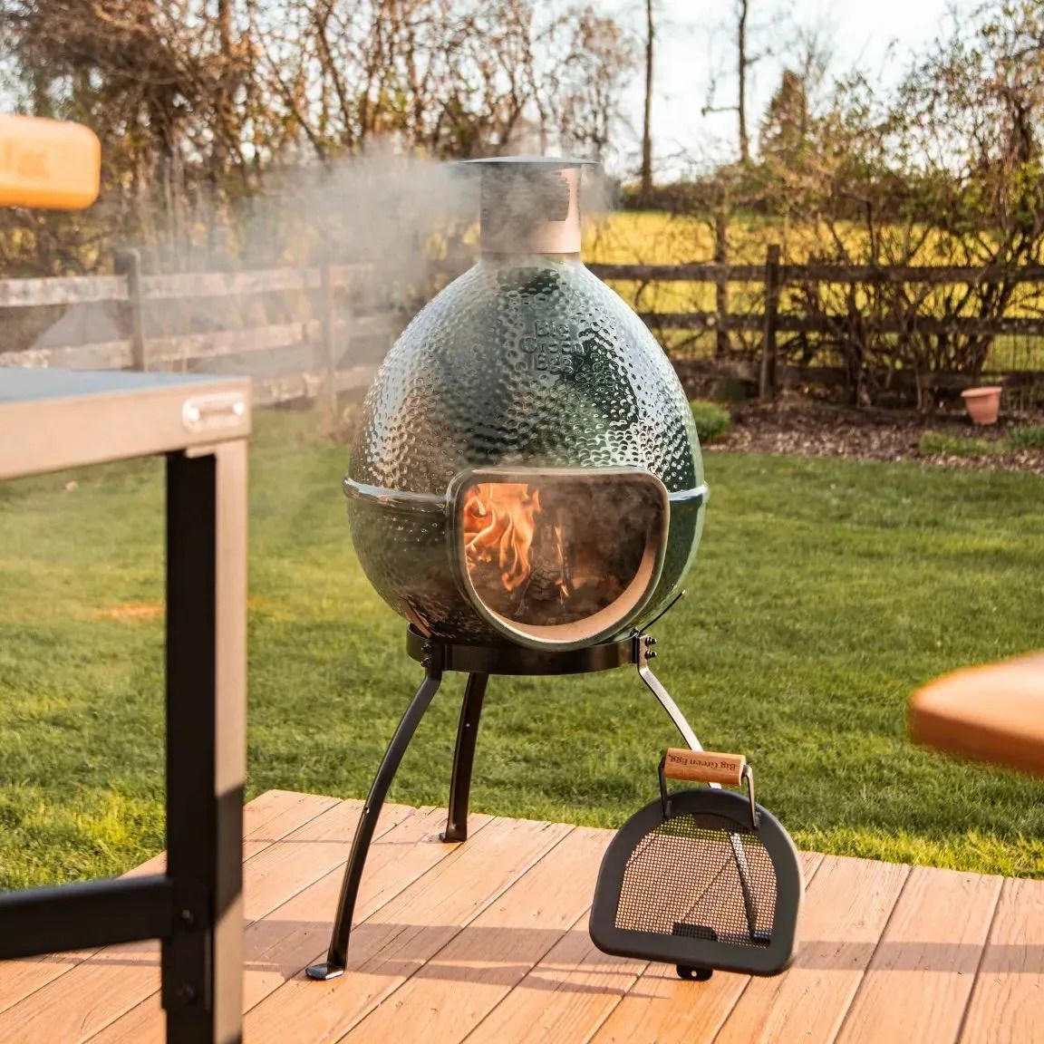 big green egg charcoal grill fired up in a grassy backyard