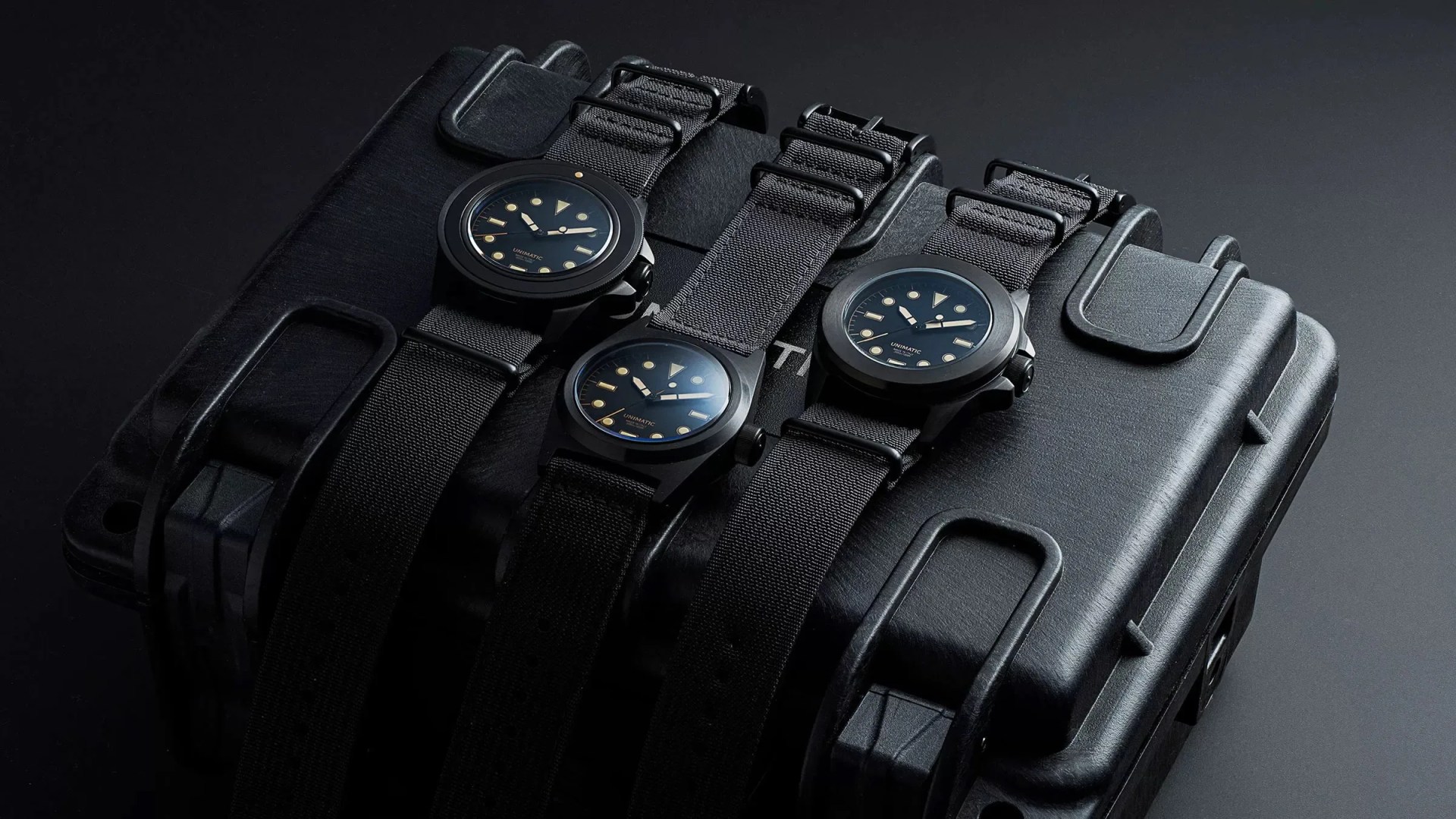 three black unimatic watches on a black pelican case
