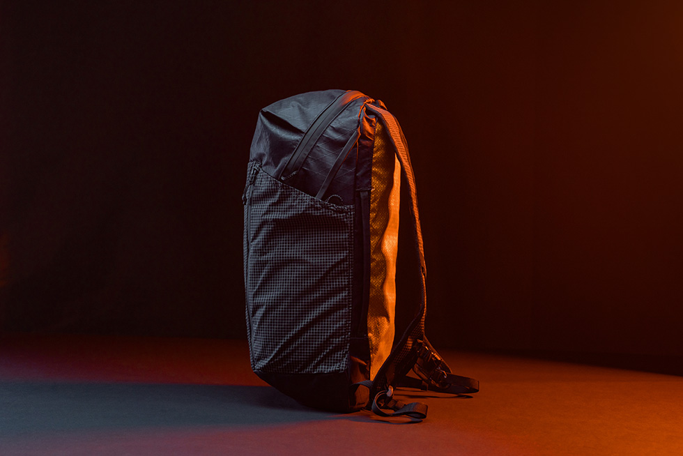 Matador x Carryology EDX Lite Backpack shown from side in dark room backlit by an organ light