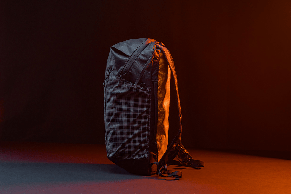 Matador x Carryology EDX Lite Backpack shown from side in dark room backlit by an organ light