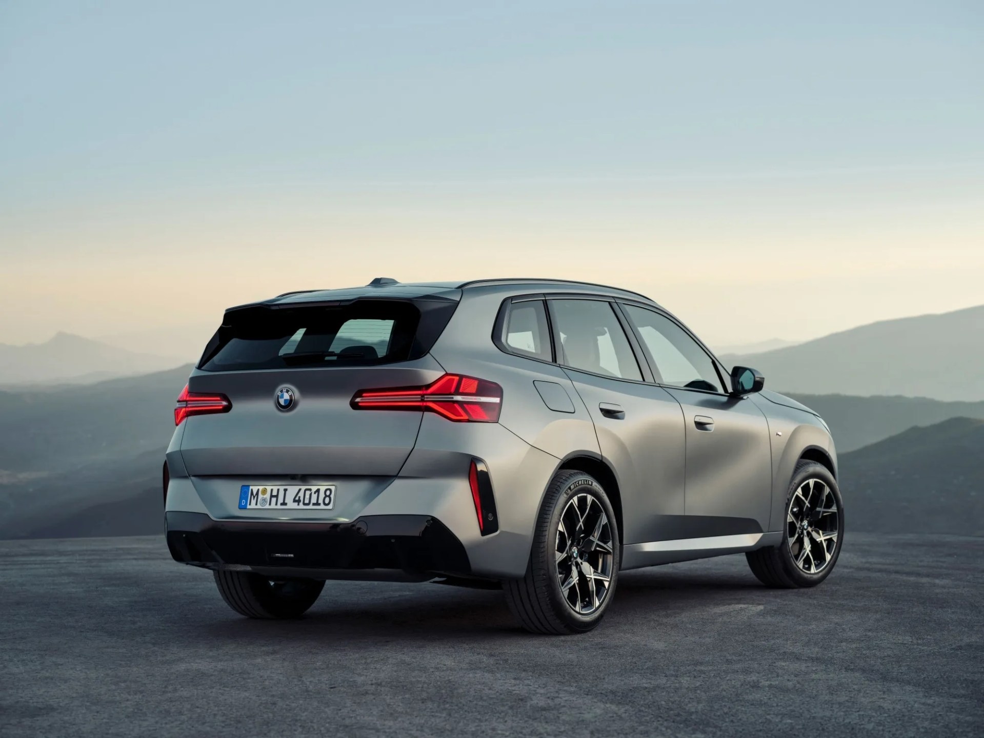 A shot of the rear corner and side of the 2025 BMW X3 in a new  Dune Grey metallic finish