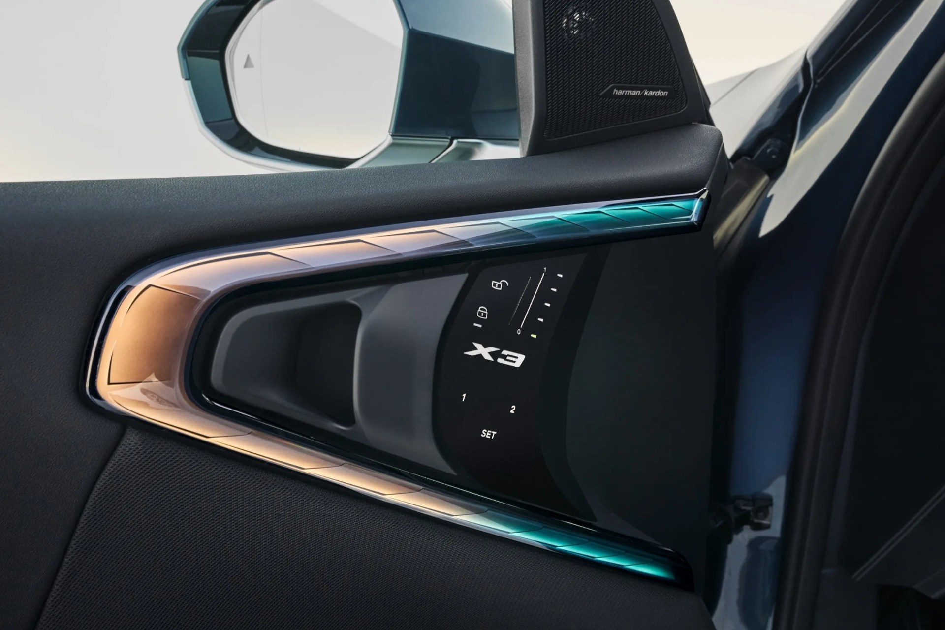 A close up of the new cabin lighting elements along the 2025 BMW X3’s driver and passenger doors which warp around the door handle and set controls in a triangular shape. 