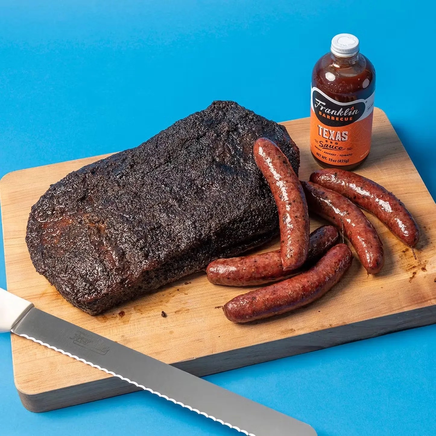 franklin barbecue brisket sausages and bbq sauce on a cutting board next to a knife
