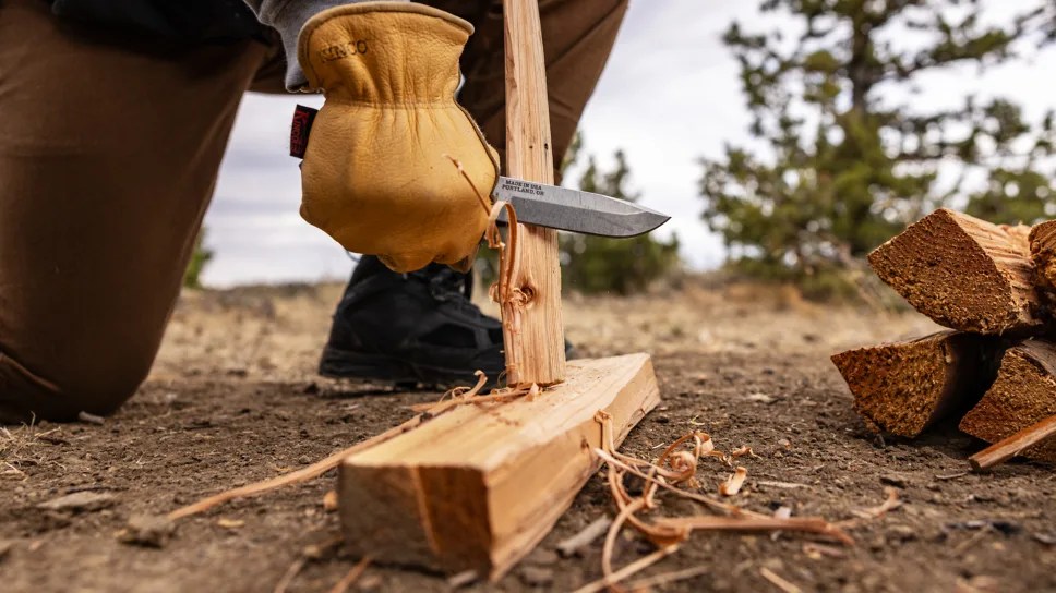 person holding making kindling with a knife