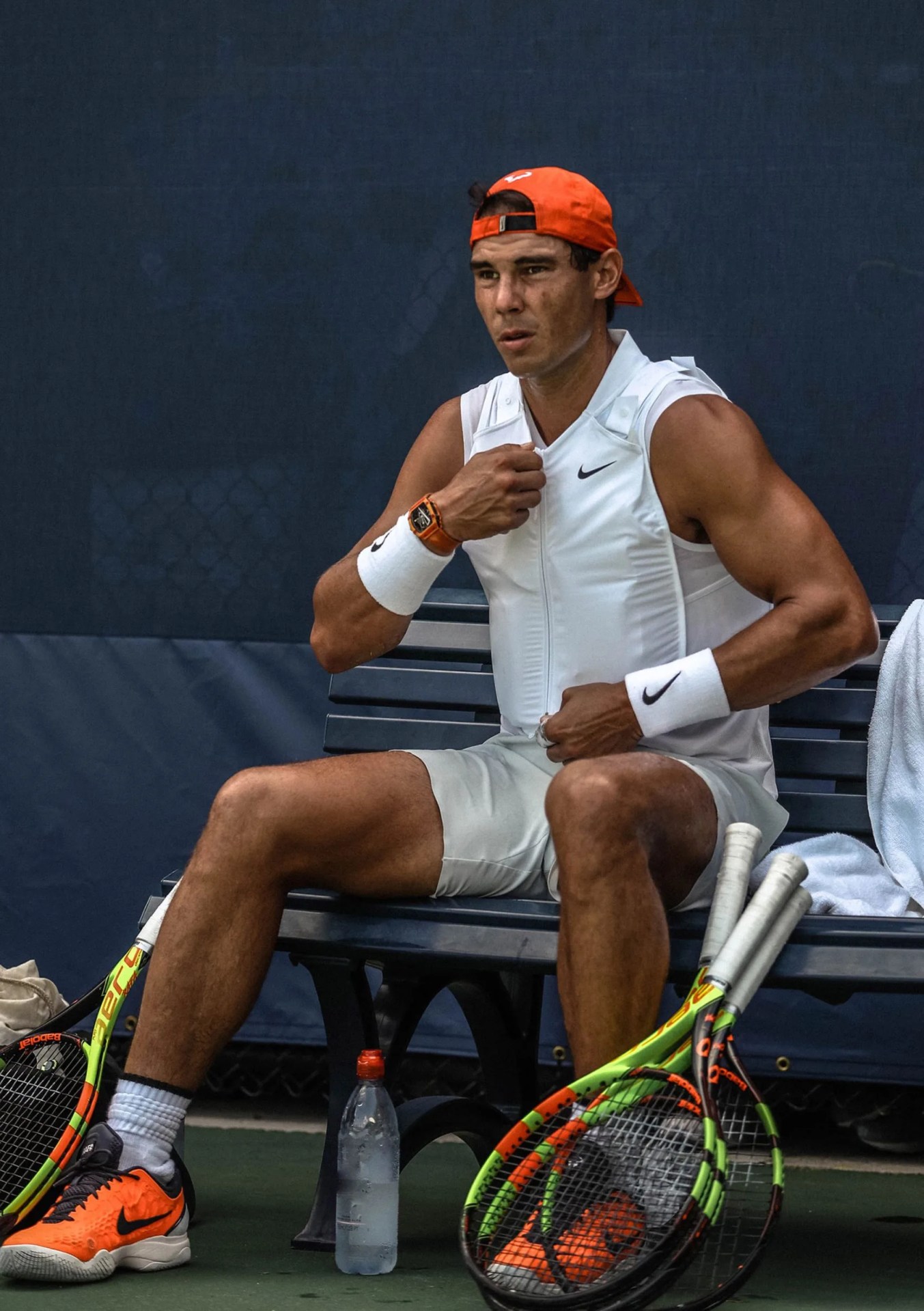 Image of Tennis superstar Raphael Nadal zipping up a white cooling vest packed with ice while sitting on a sideline bench during the 2018 U.S. Open