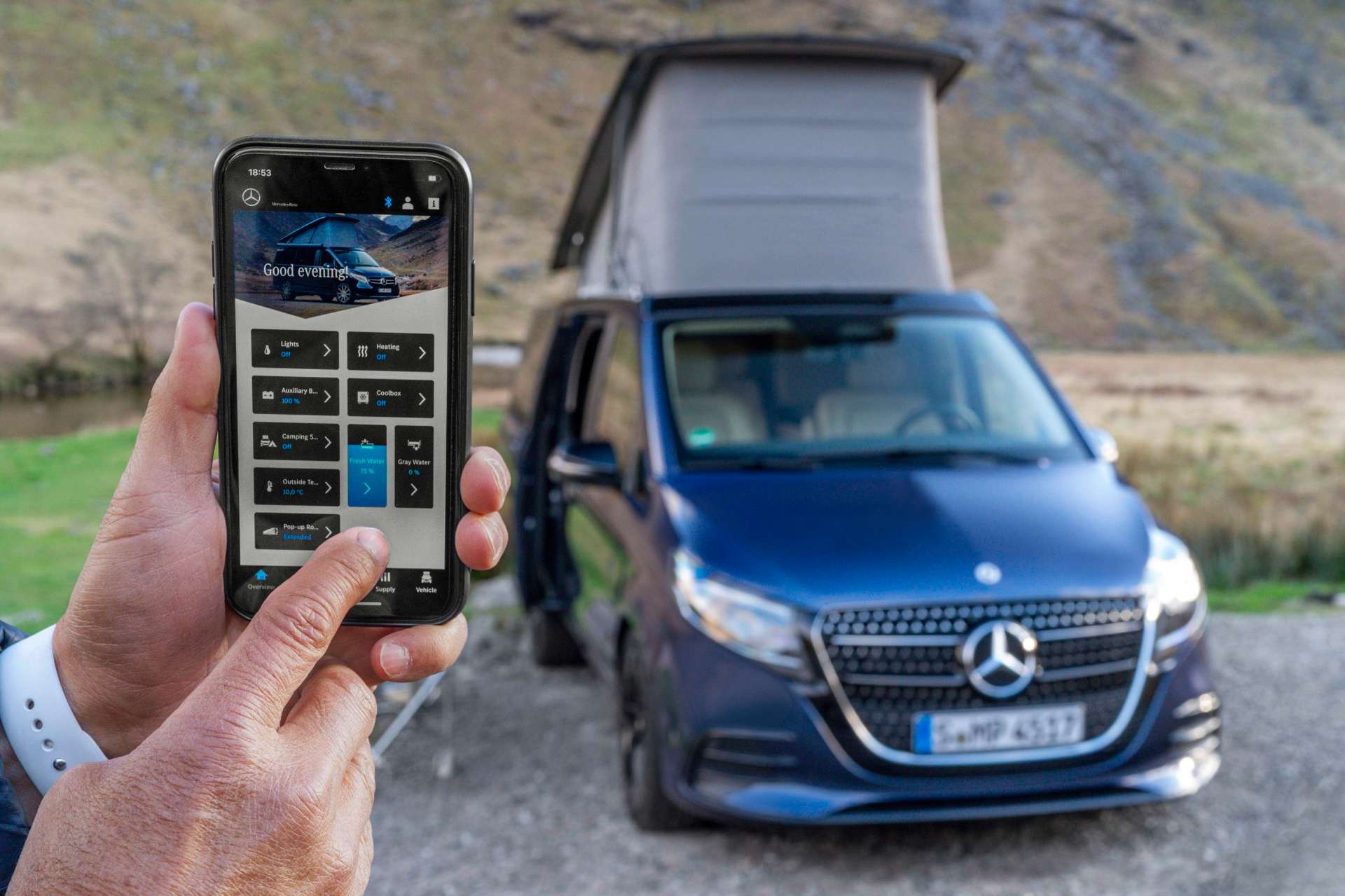 person uses a smartphone to control a mercedes camper van