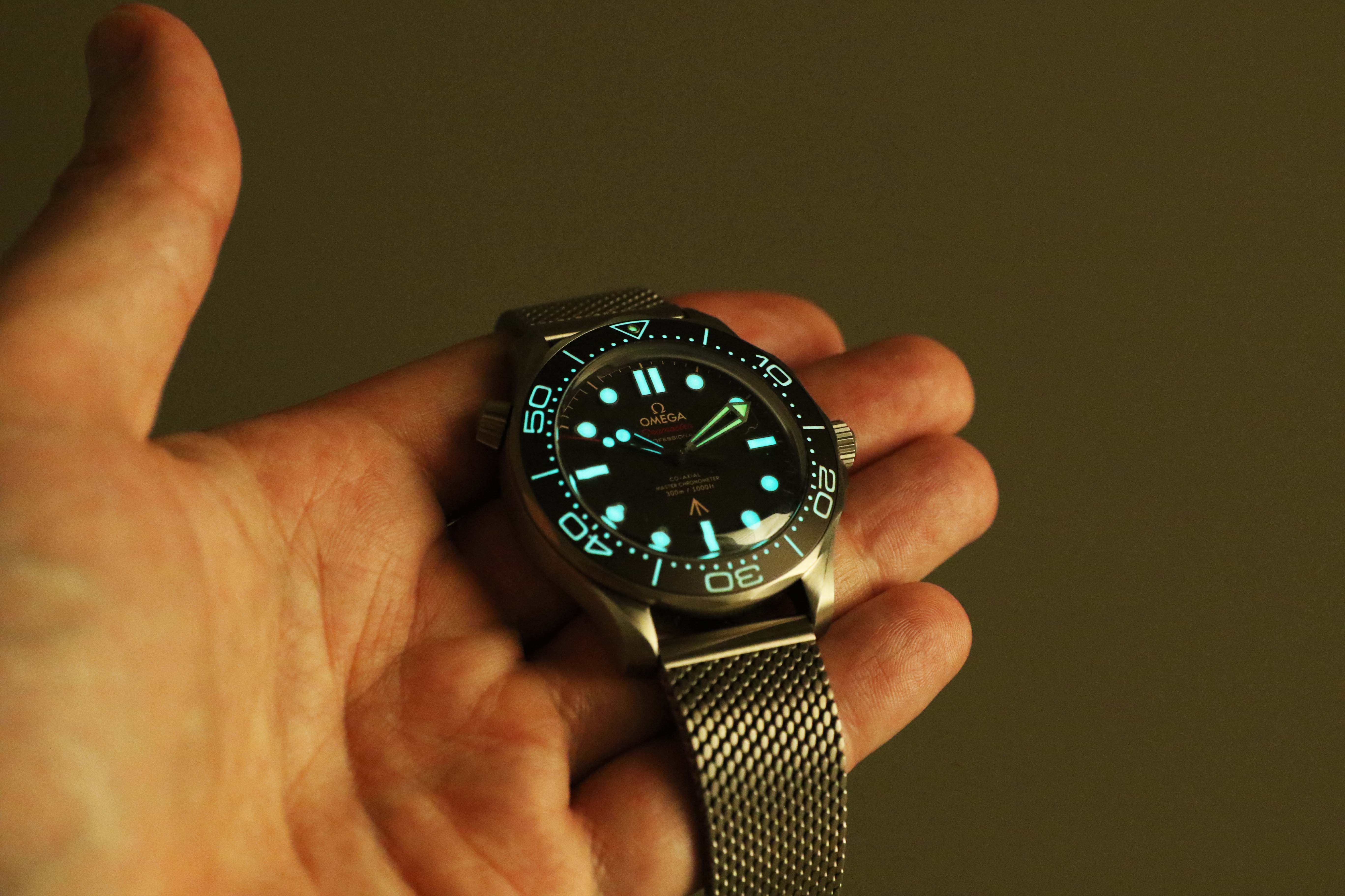 omega watch glowing in the dark held by a hand