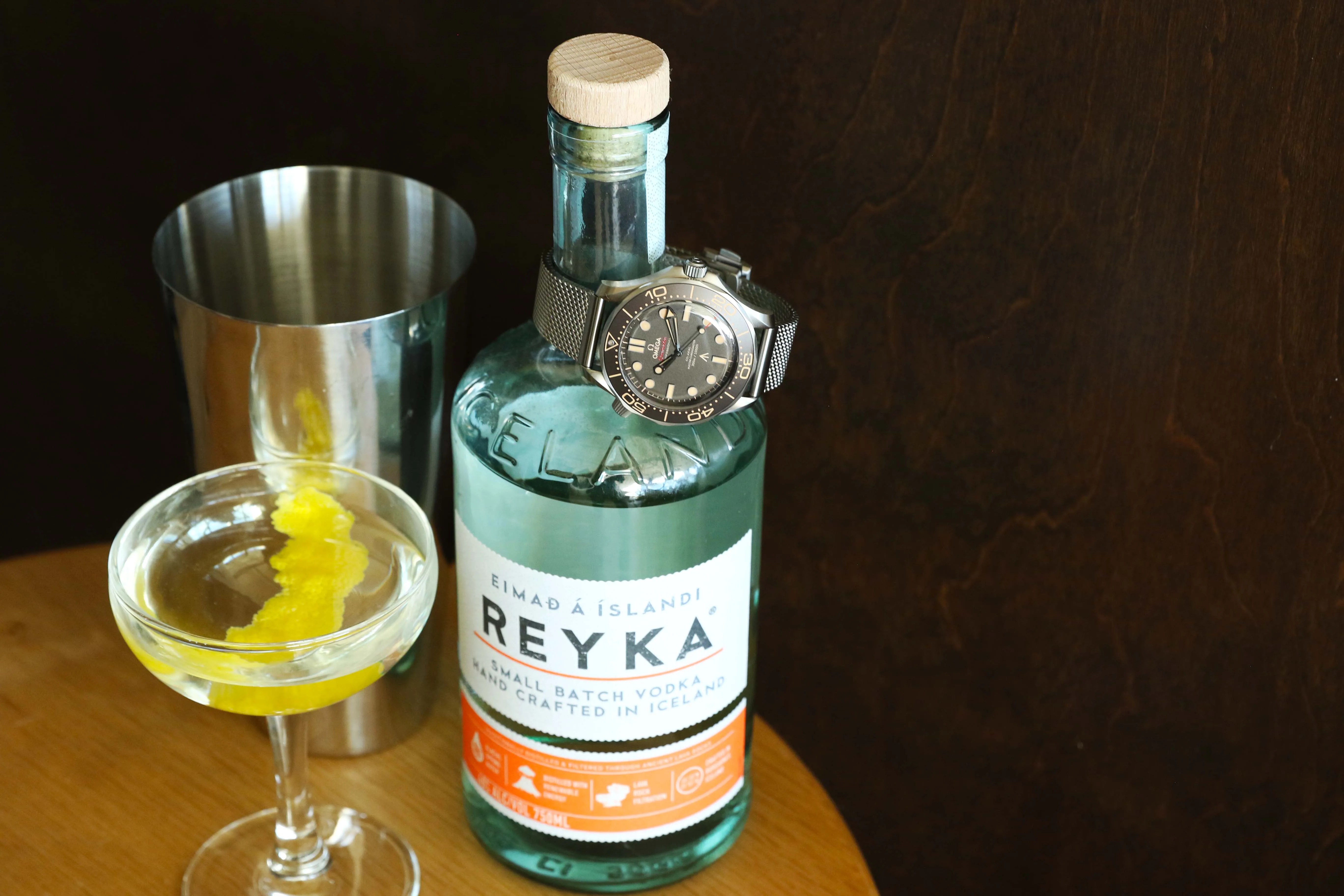 omega watch on a bottle of vodka next to a martini