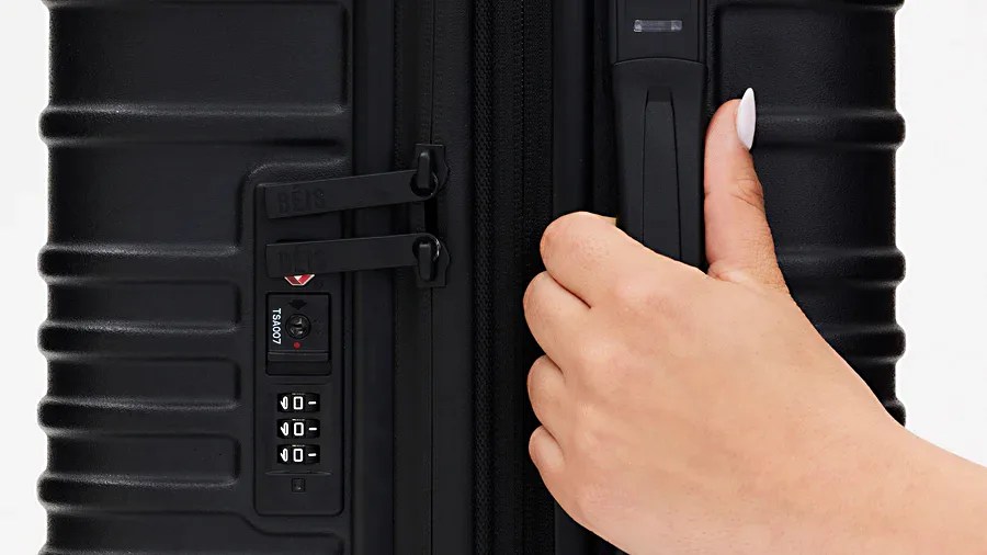 person holding handle of a black suitcase