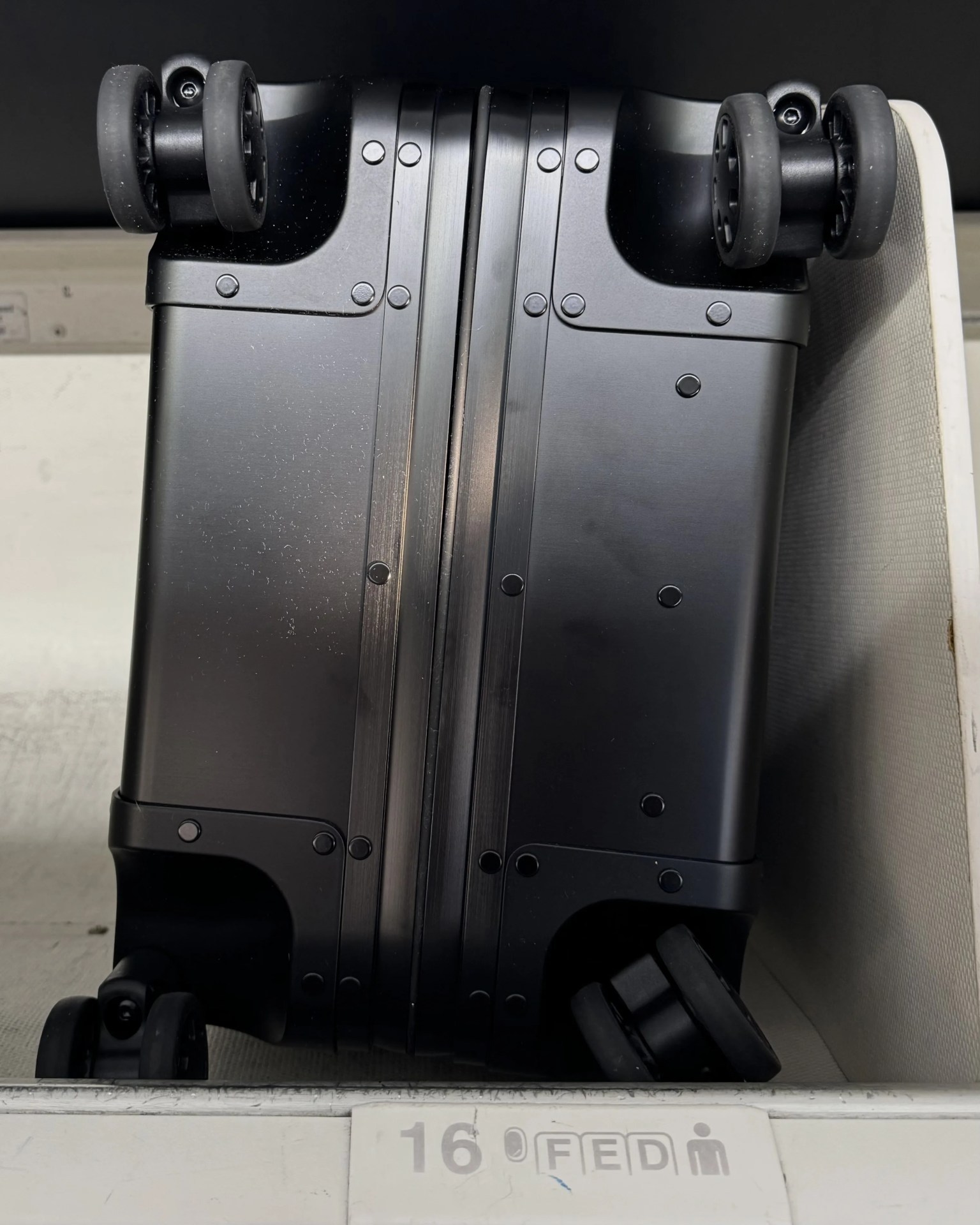 Sterling Pacific 40L Cabin Travel Case in black pushed into airline overhead bin with the wheels out. 