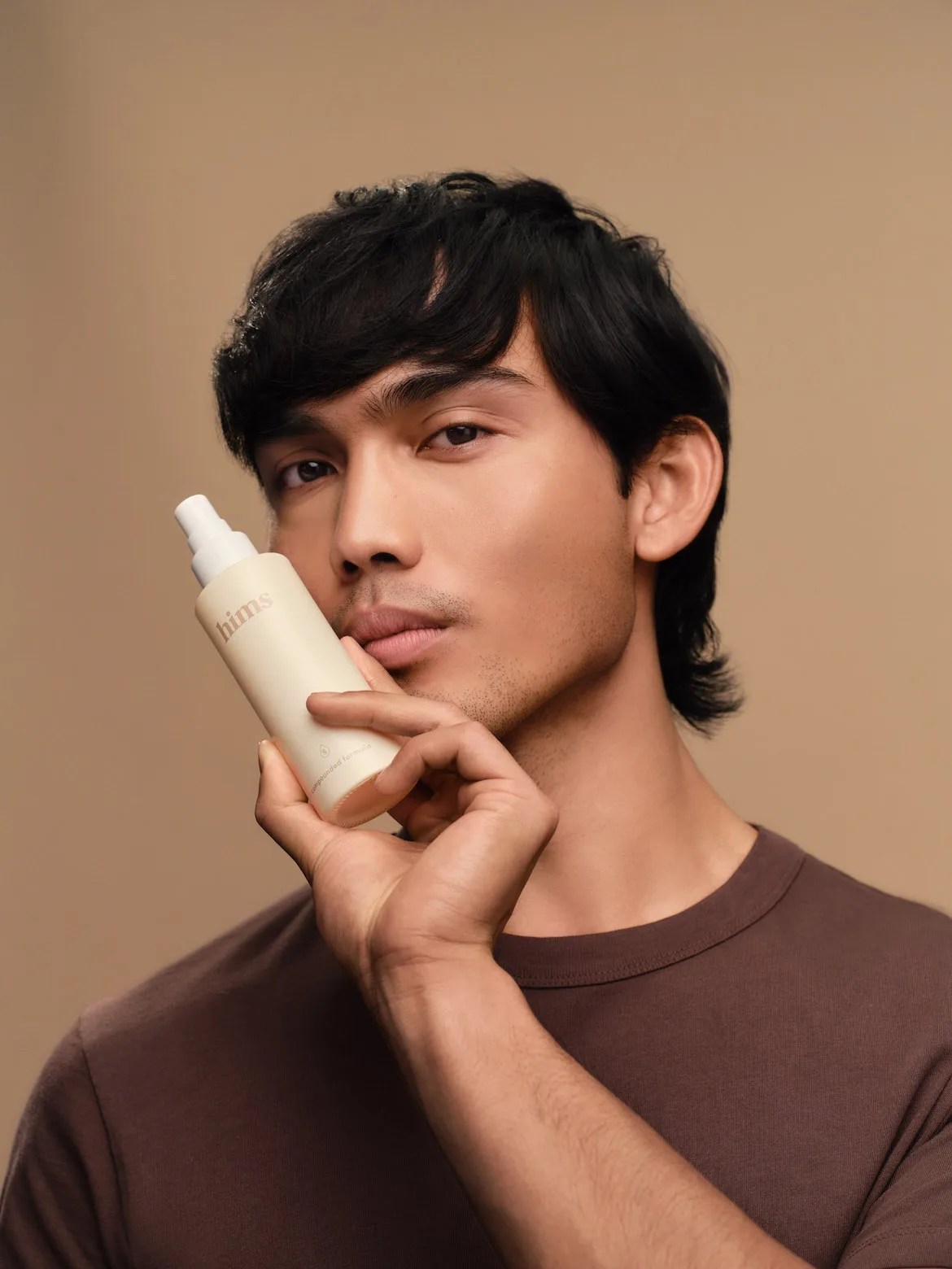 Man with black hair holding hair loss bottle