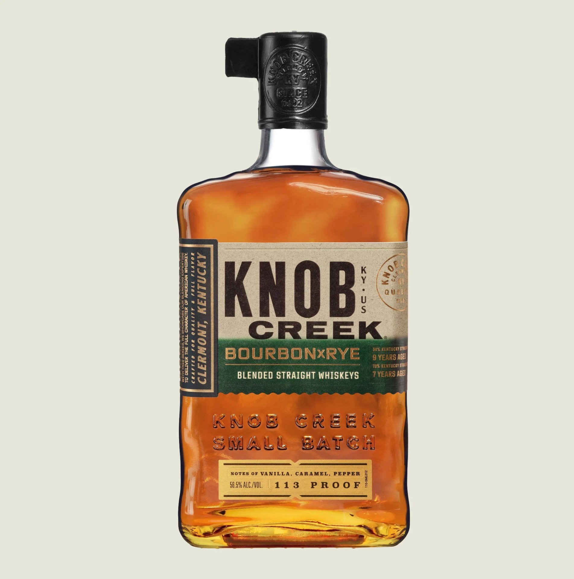 A bottle of Knob Creek Bourbon x Rye on a tan colored background