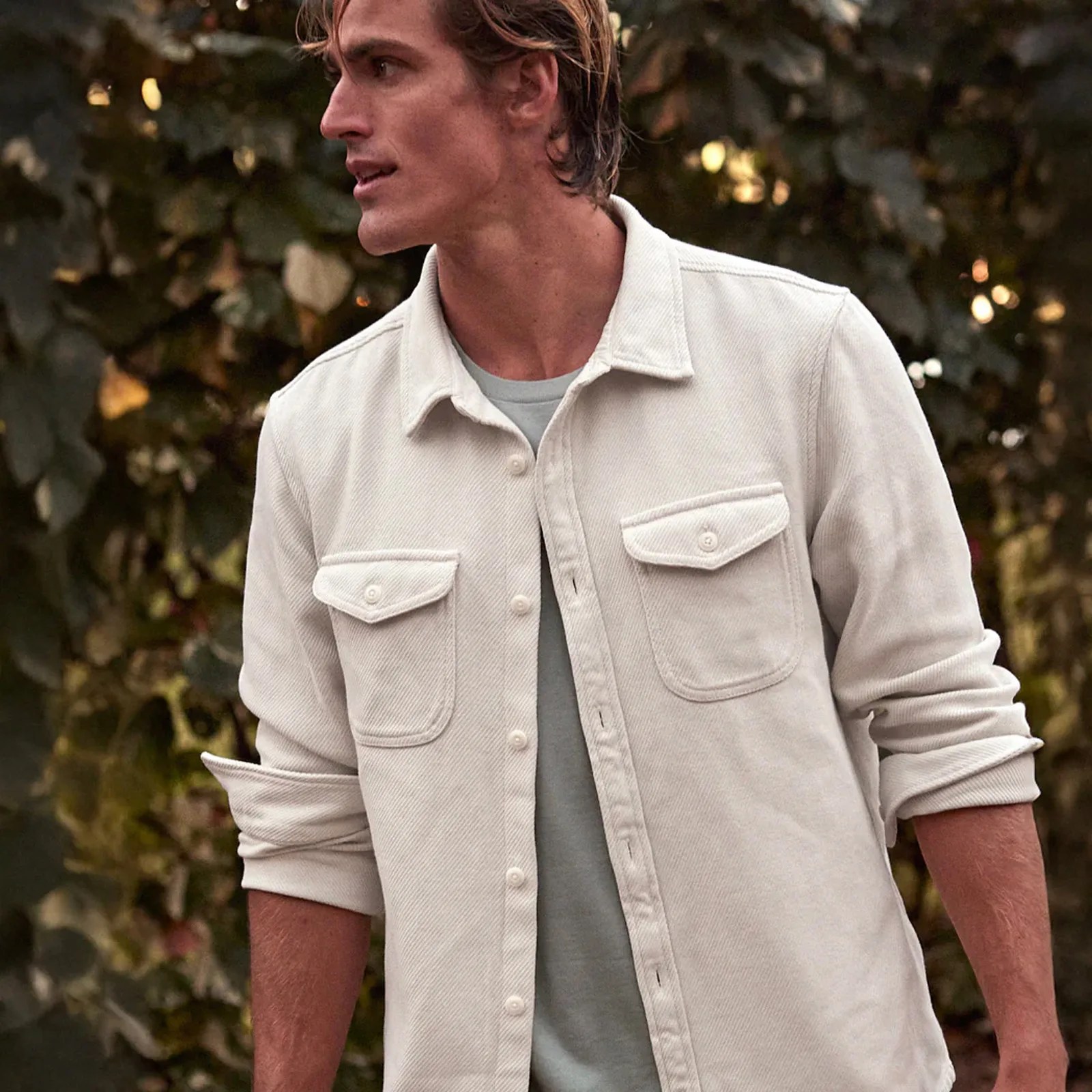 A man wearing a white colored Chroma Blanket overshirt from Outerknown