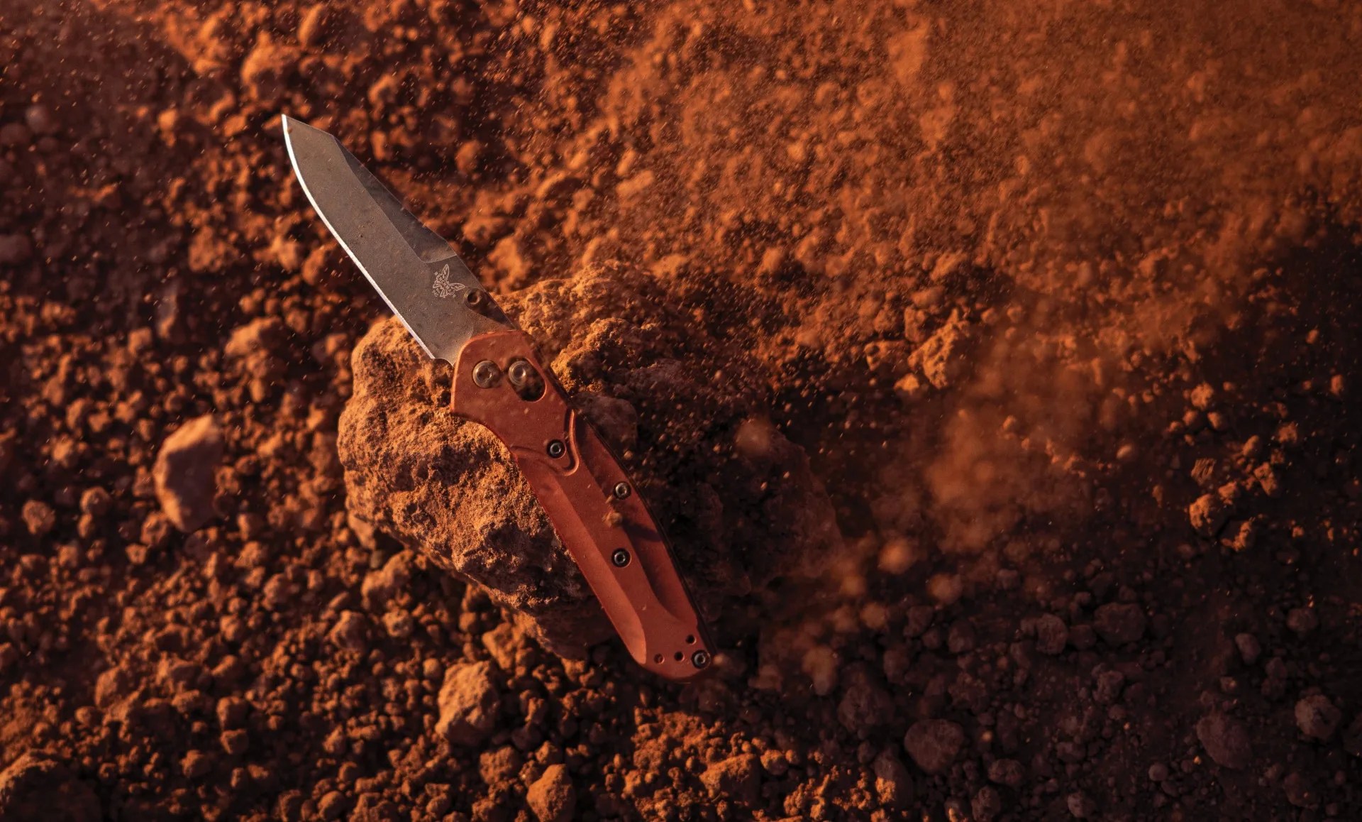 a benchmade pocket knife on some red clay