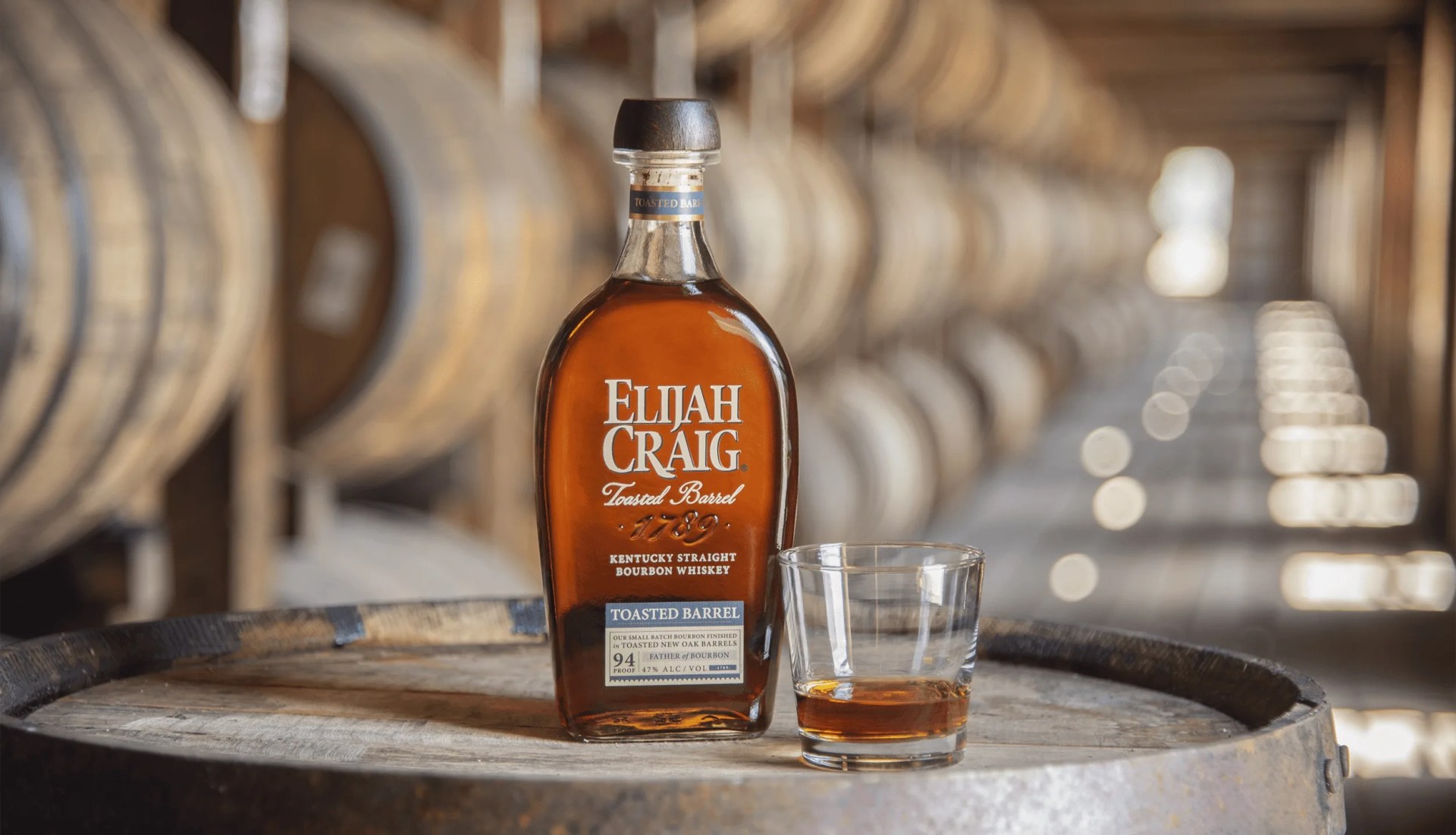 elijah craig bourbon bottle and glass in a rickhouse