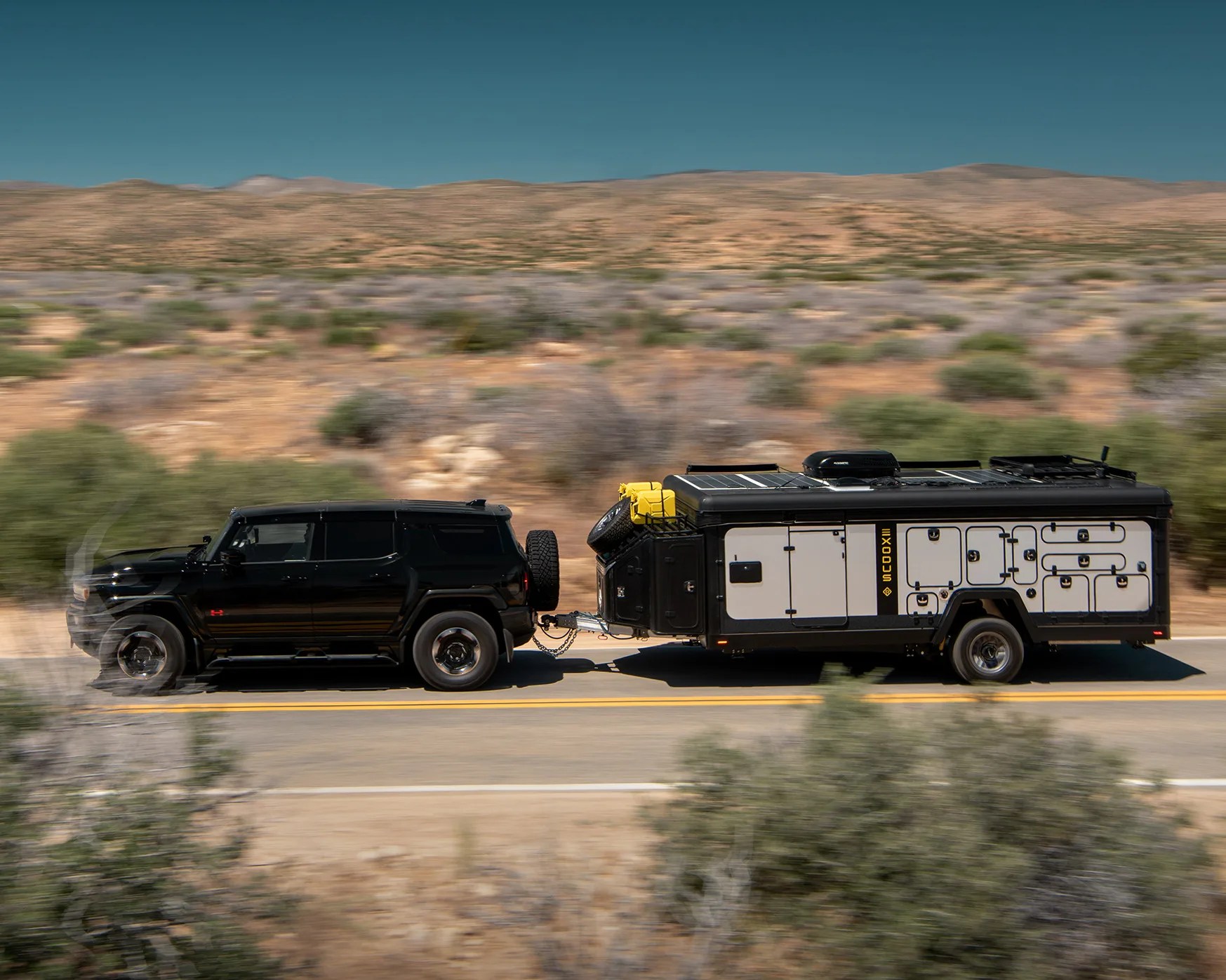 an suv tows an exodus camper on a desert road