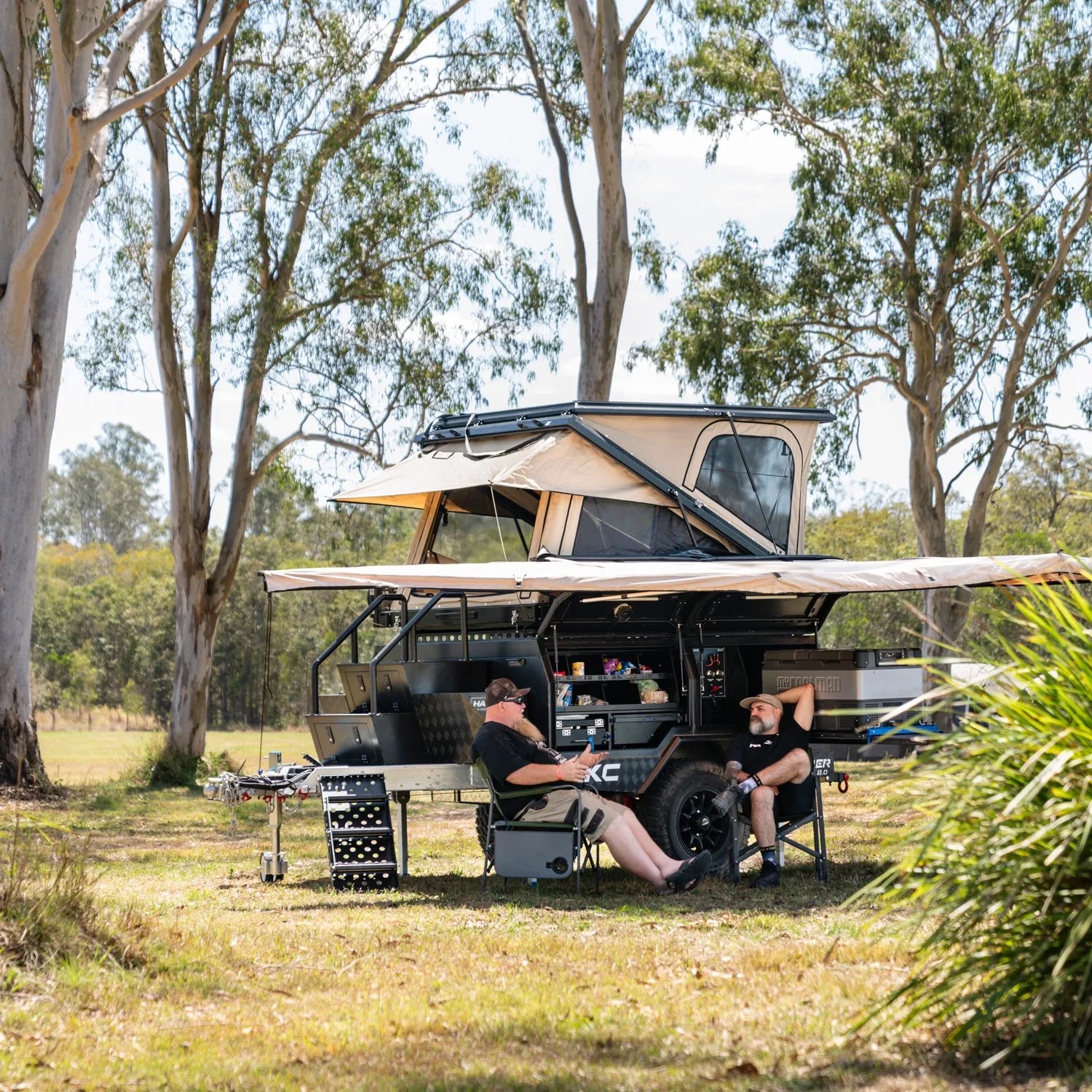 two campers hang out in front of a hardkore campers trailer