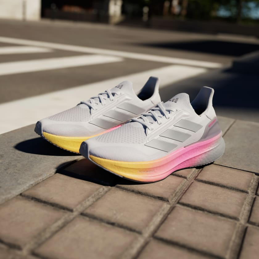 A pair of Adidas Ultraboost 5X running shoes sitting on street crosswalk at an angle.