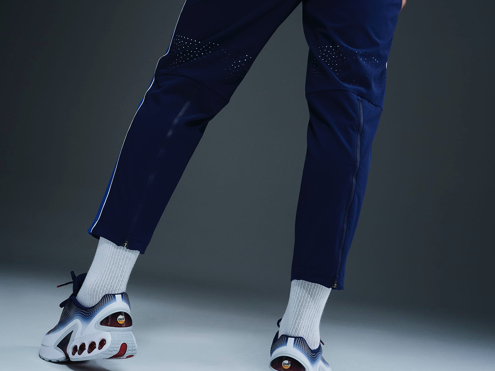 An image of an athlete’s back legs wearing Nike’s dark blue Team USA medal podium pant highlighting the pant’s integrated vents behind the knee area. 