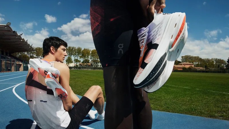 two runners on a track holding running shoes