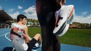two runners on a track holding running shoes