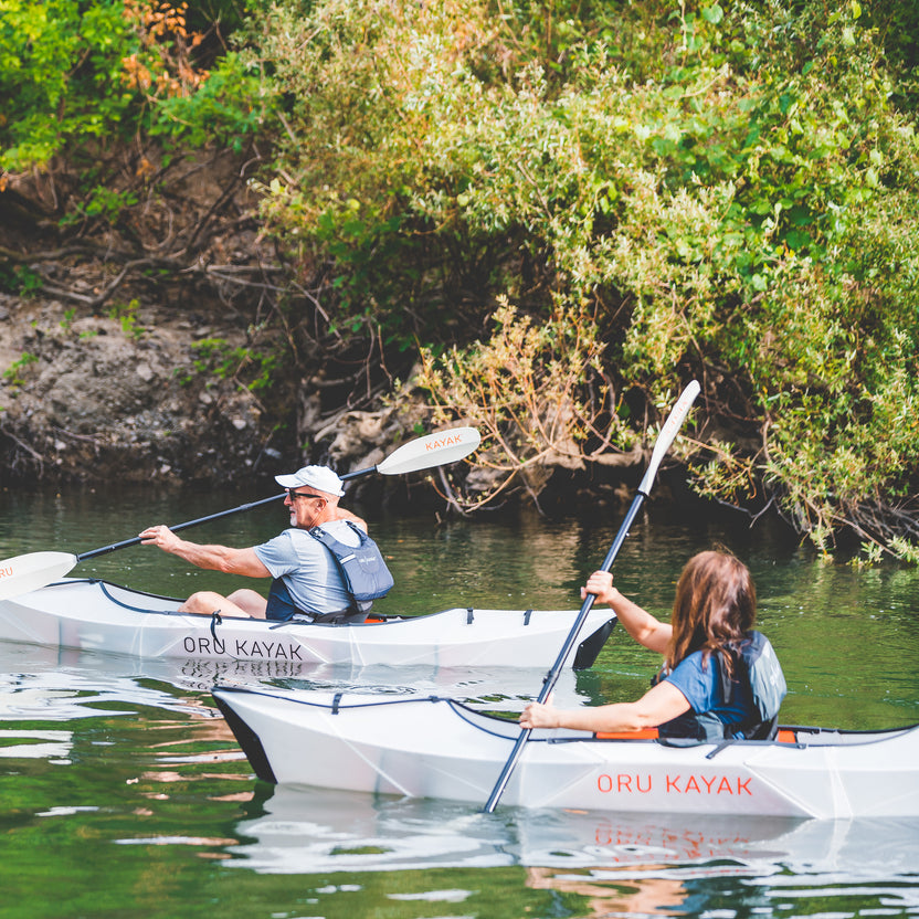 two people kayaking in a small river
