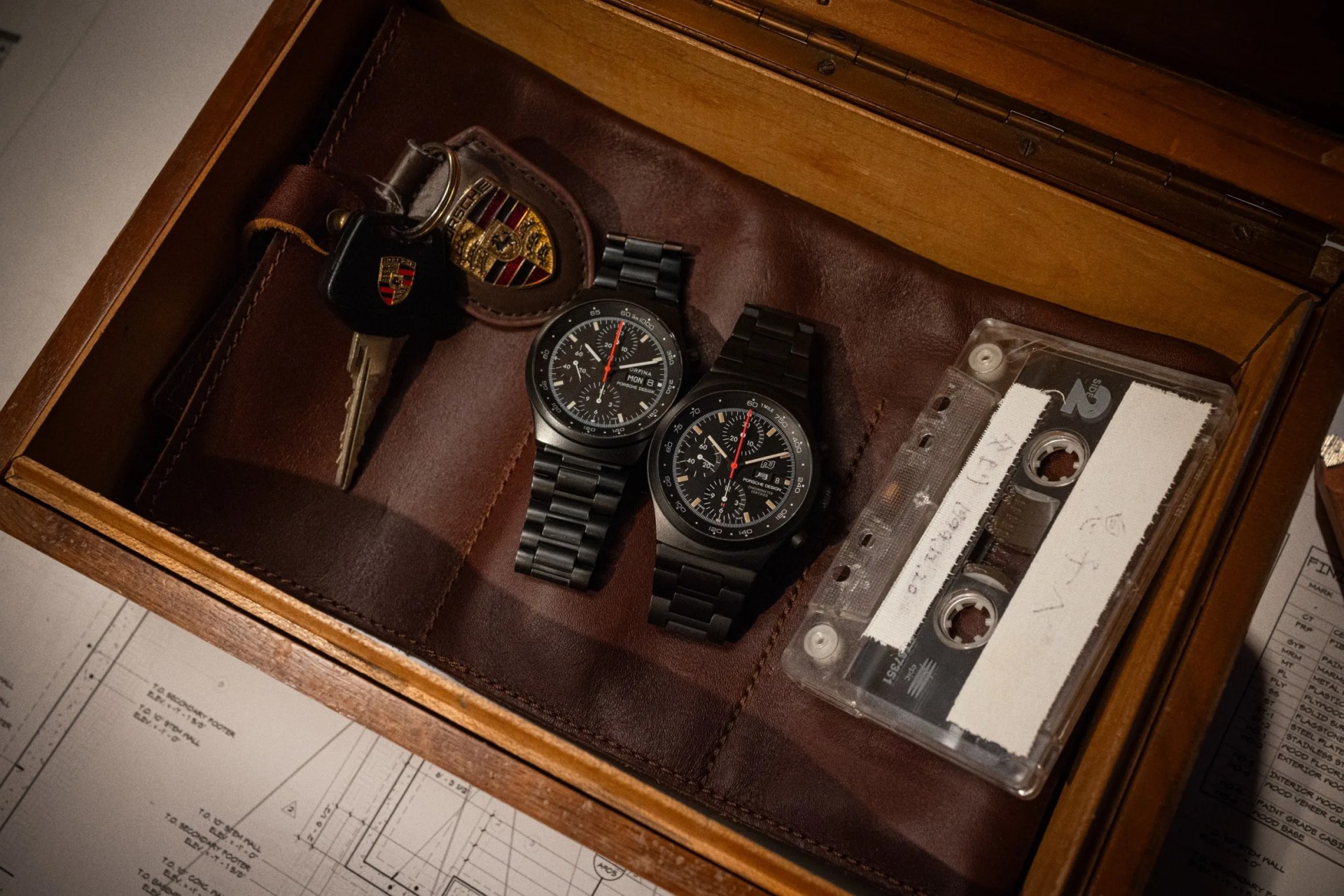 two porsche design watches in a drawer next to car keys and a cassette tape
