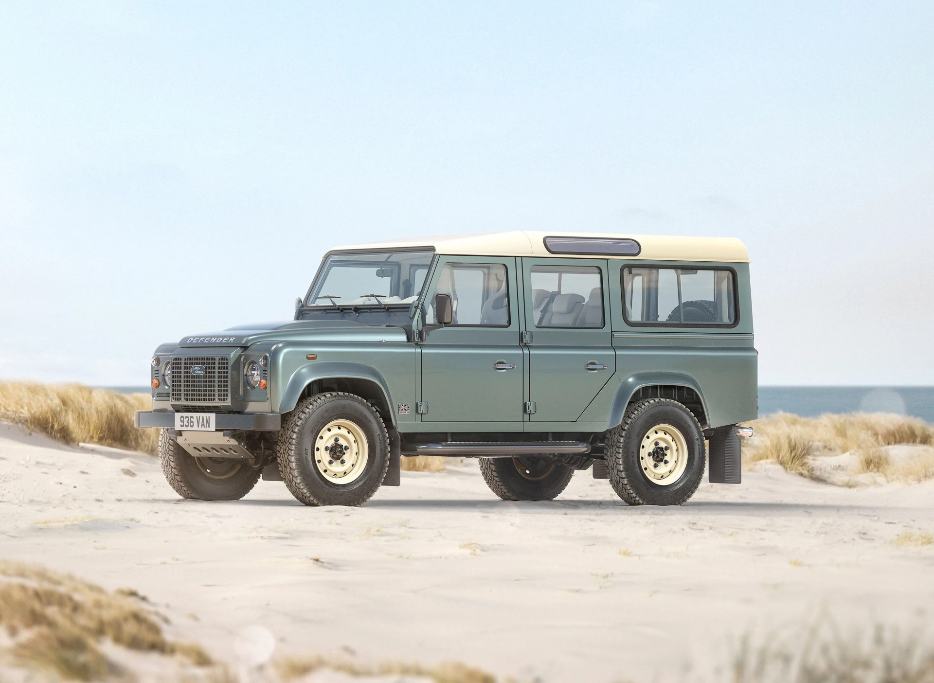 A classic Land Rover Defender 110 sitting on a beach