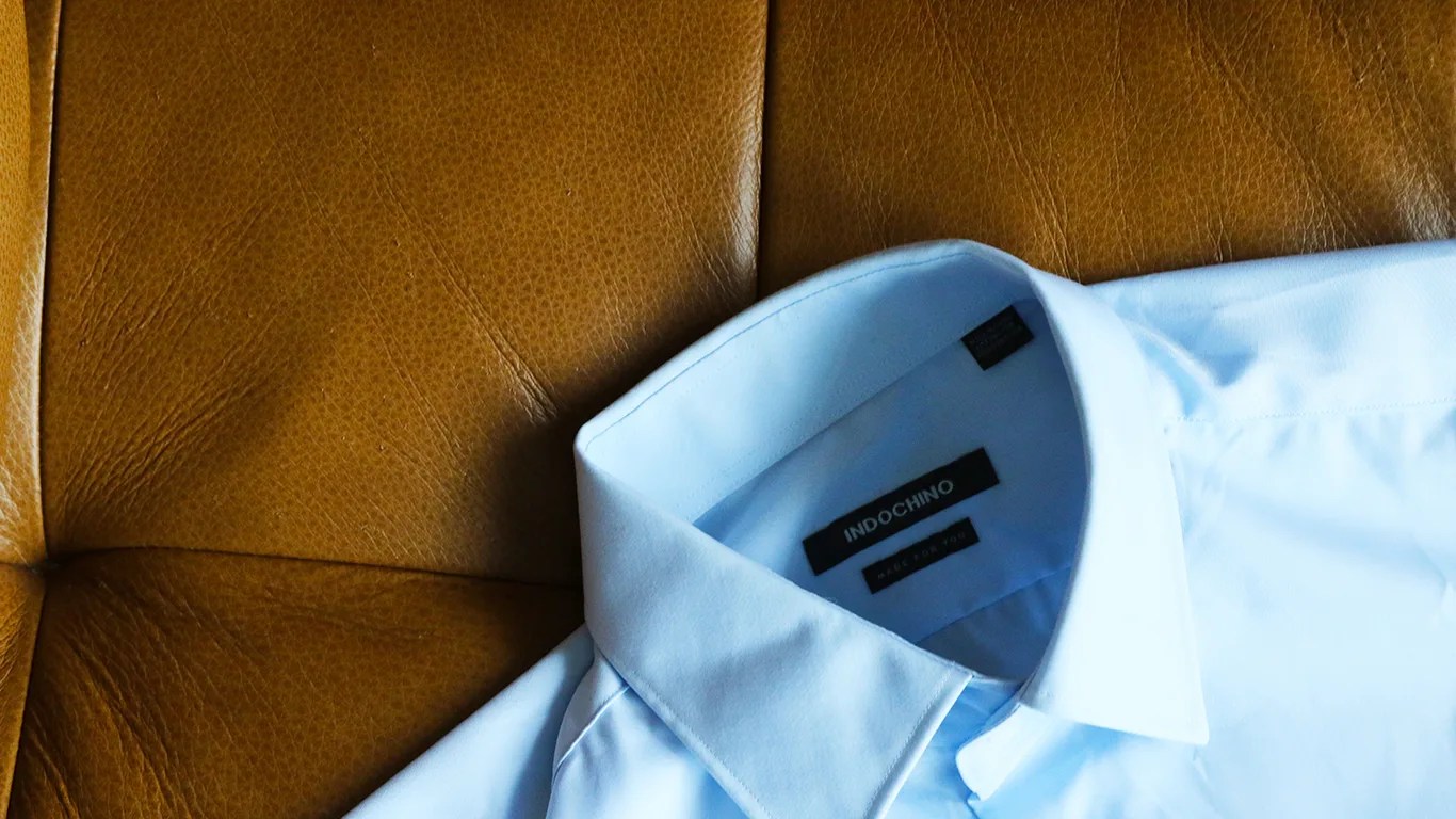 a blue dress shirt on a tan leather couch