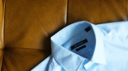 a blue dress shirt on a tan leather couch