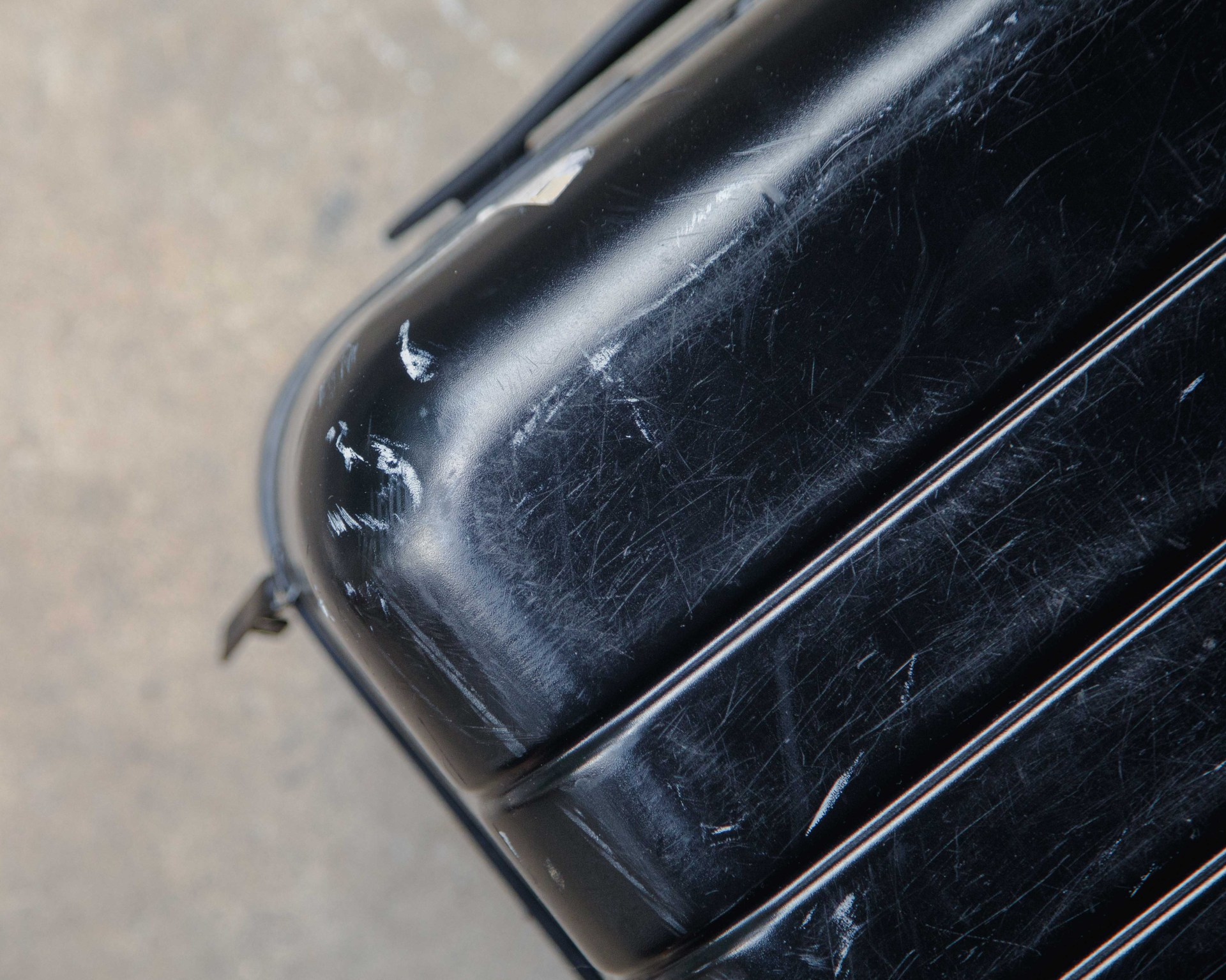 a black hardshell suitcase with scuffs