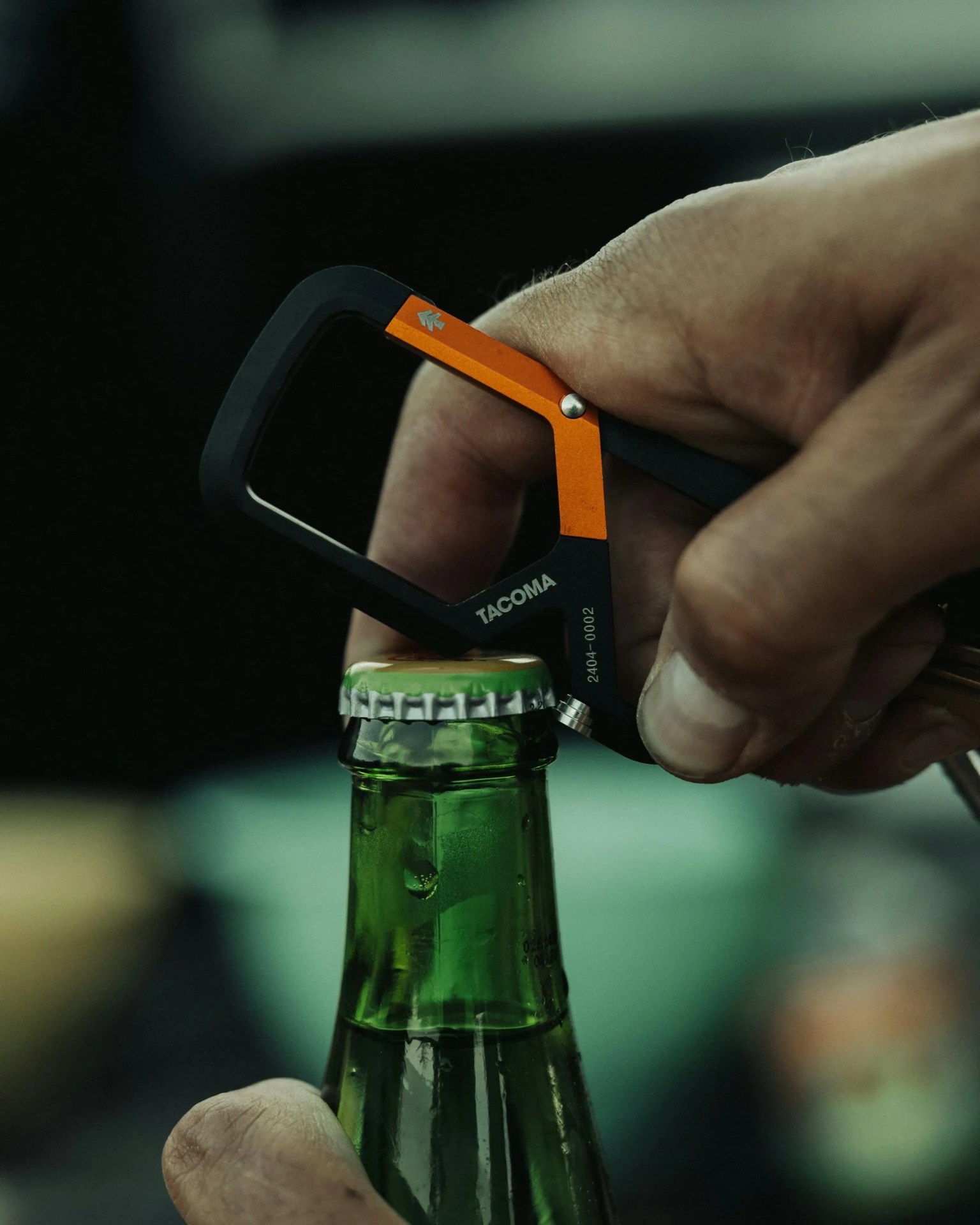 a tacoma branded james brand carabiner from huckberry is used to open a beer bottle