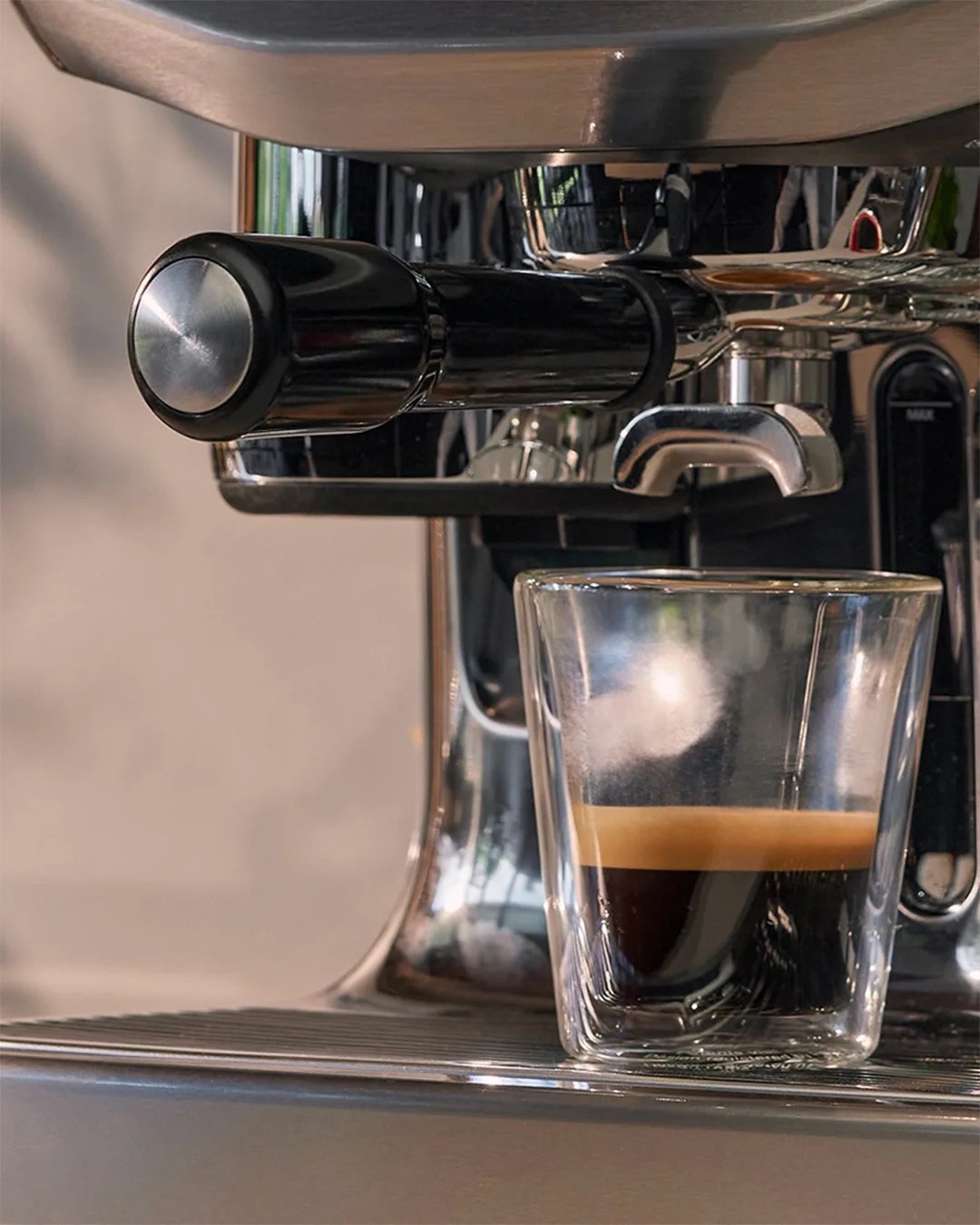 Close up shot of Breville Oracle Jet with filled espresso cup sitting on it. 