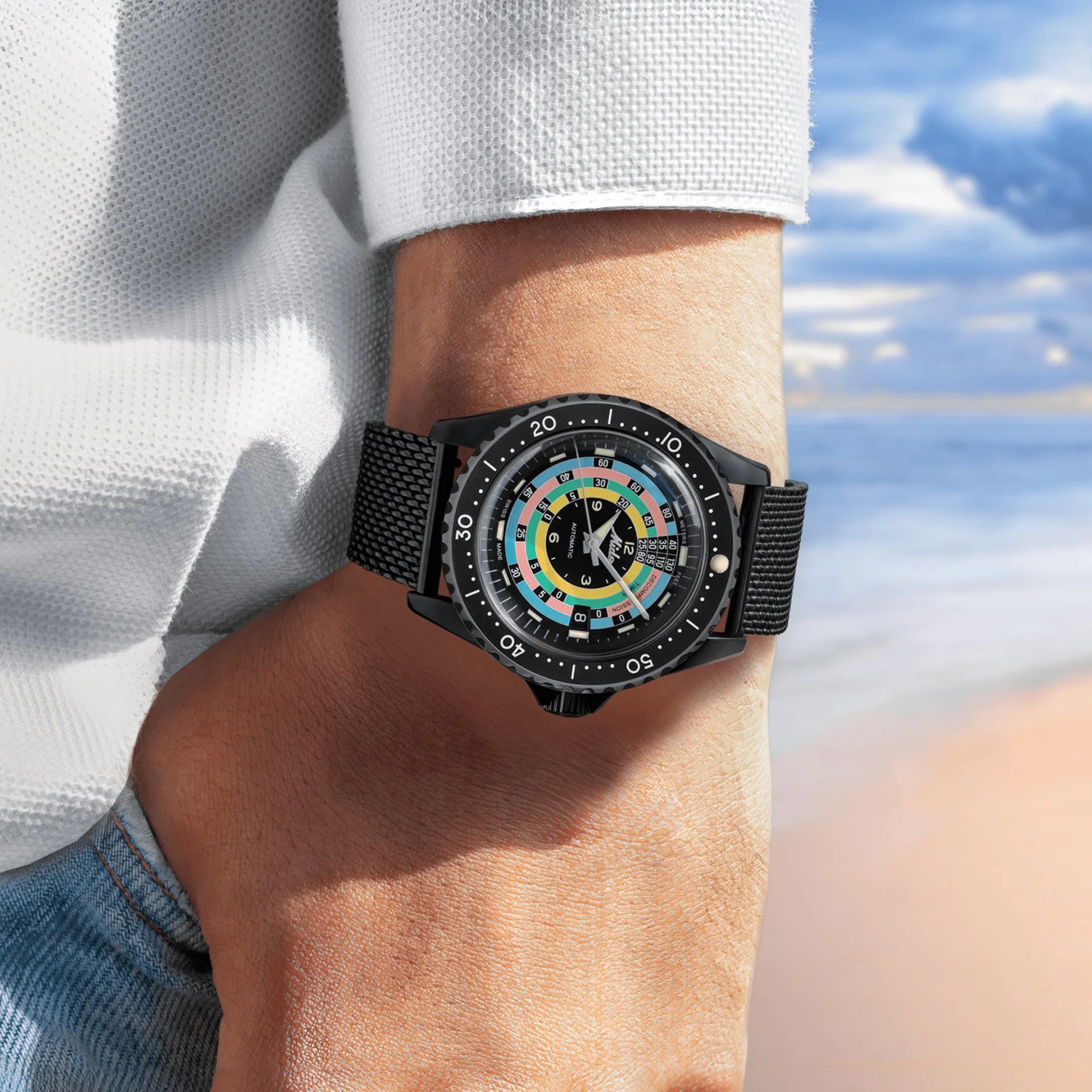 closeup of a mido dive watch on a mans wrist at the beach