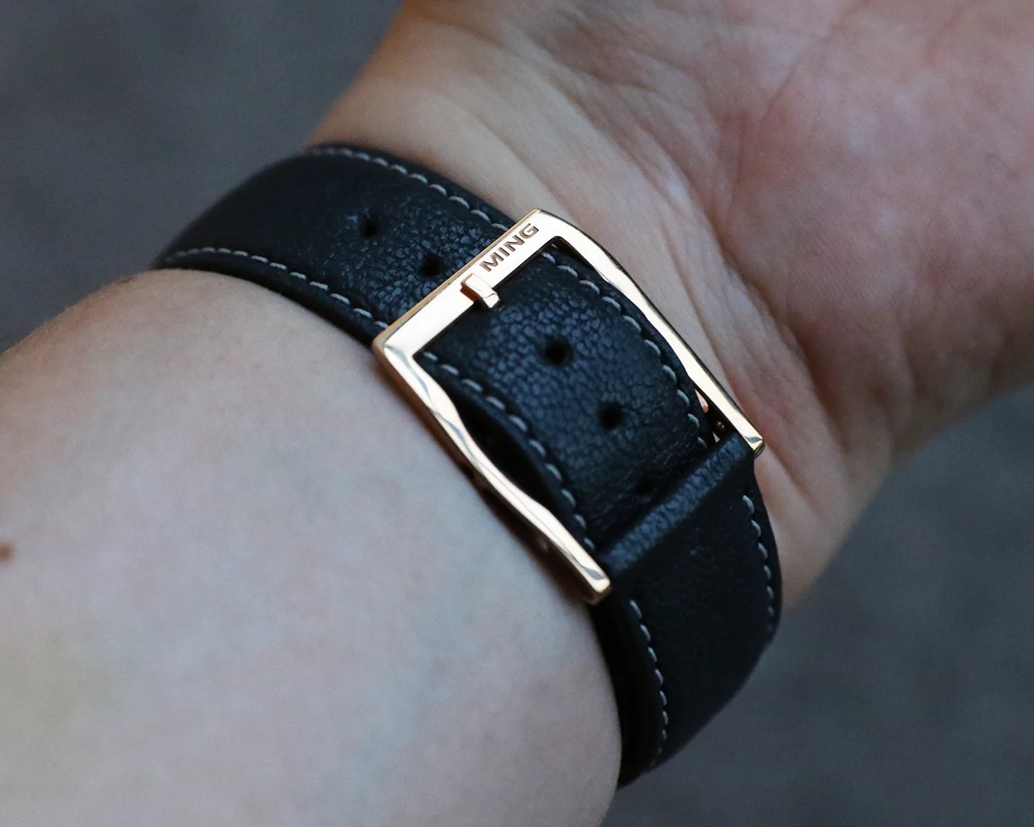 a ming watch strap and buckle on a mans wrist