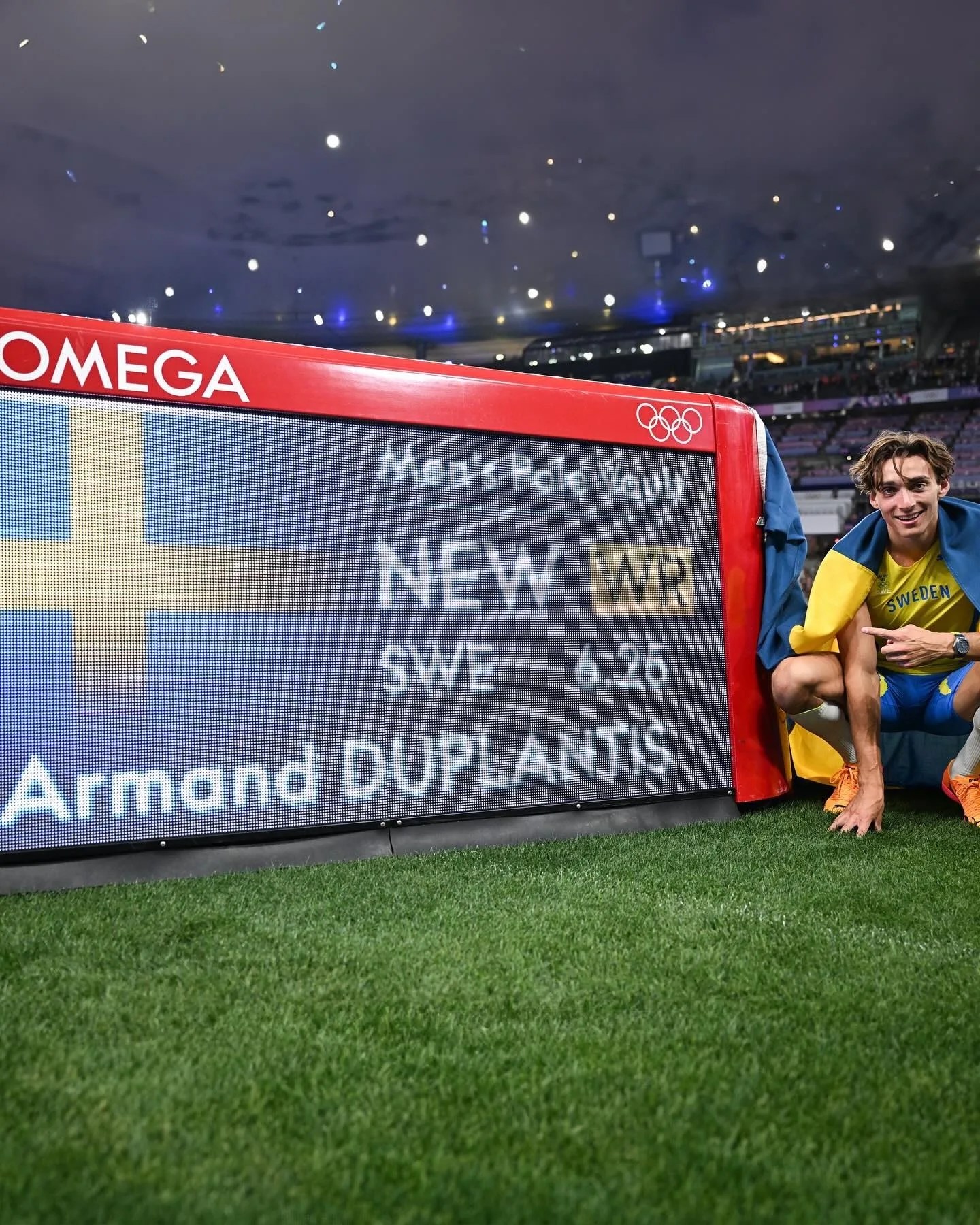 mondo duplantis poses next to his world record sign wearing an omega watch