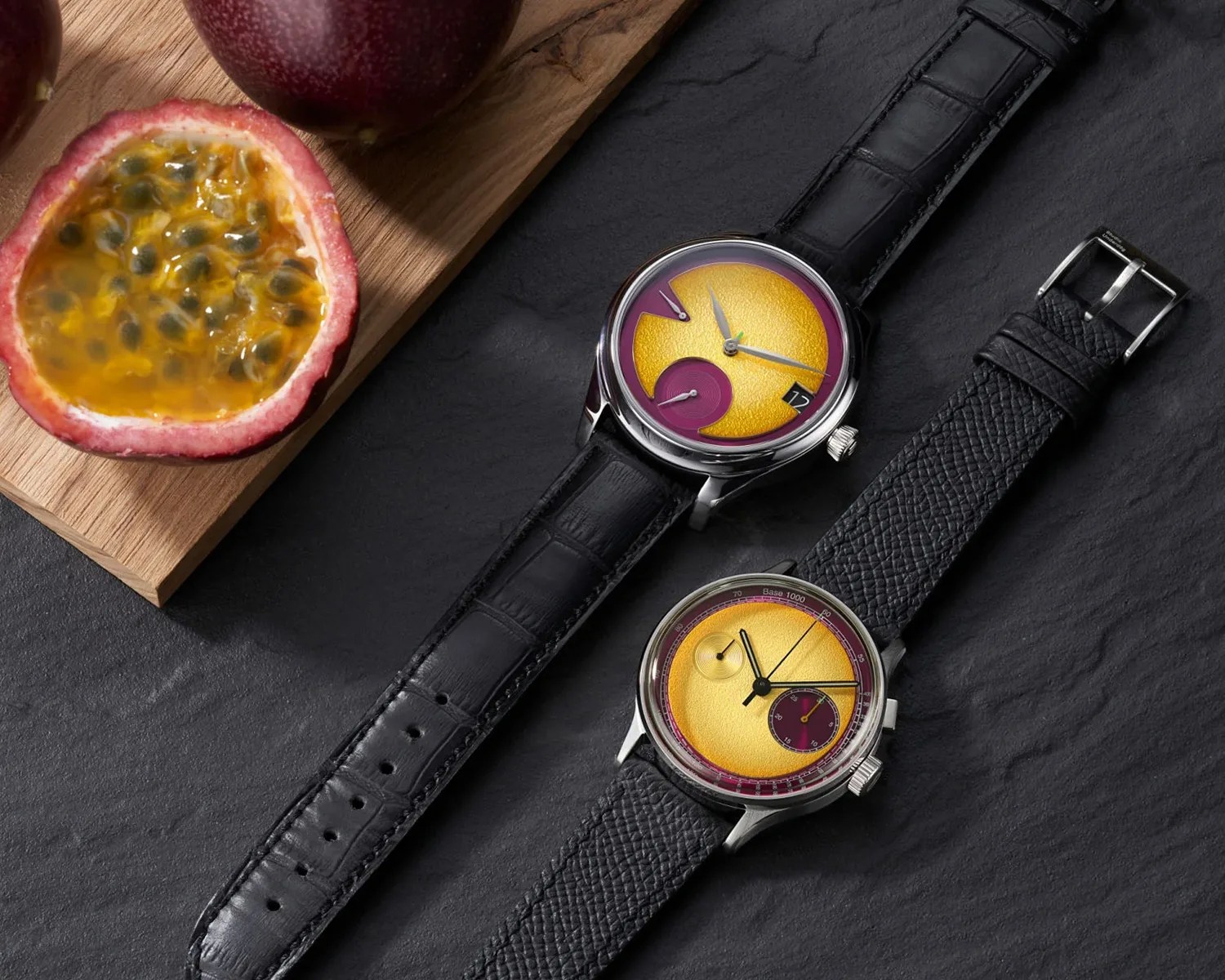 a studio underd0g watch next to a moser watch on a table next to a passion fruit