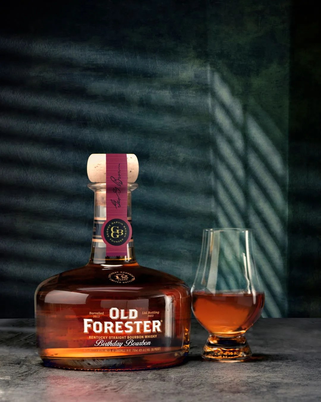 a bottle of old forester bourbon next to a glass