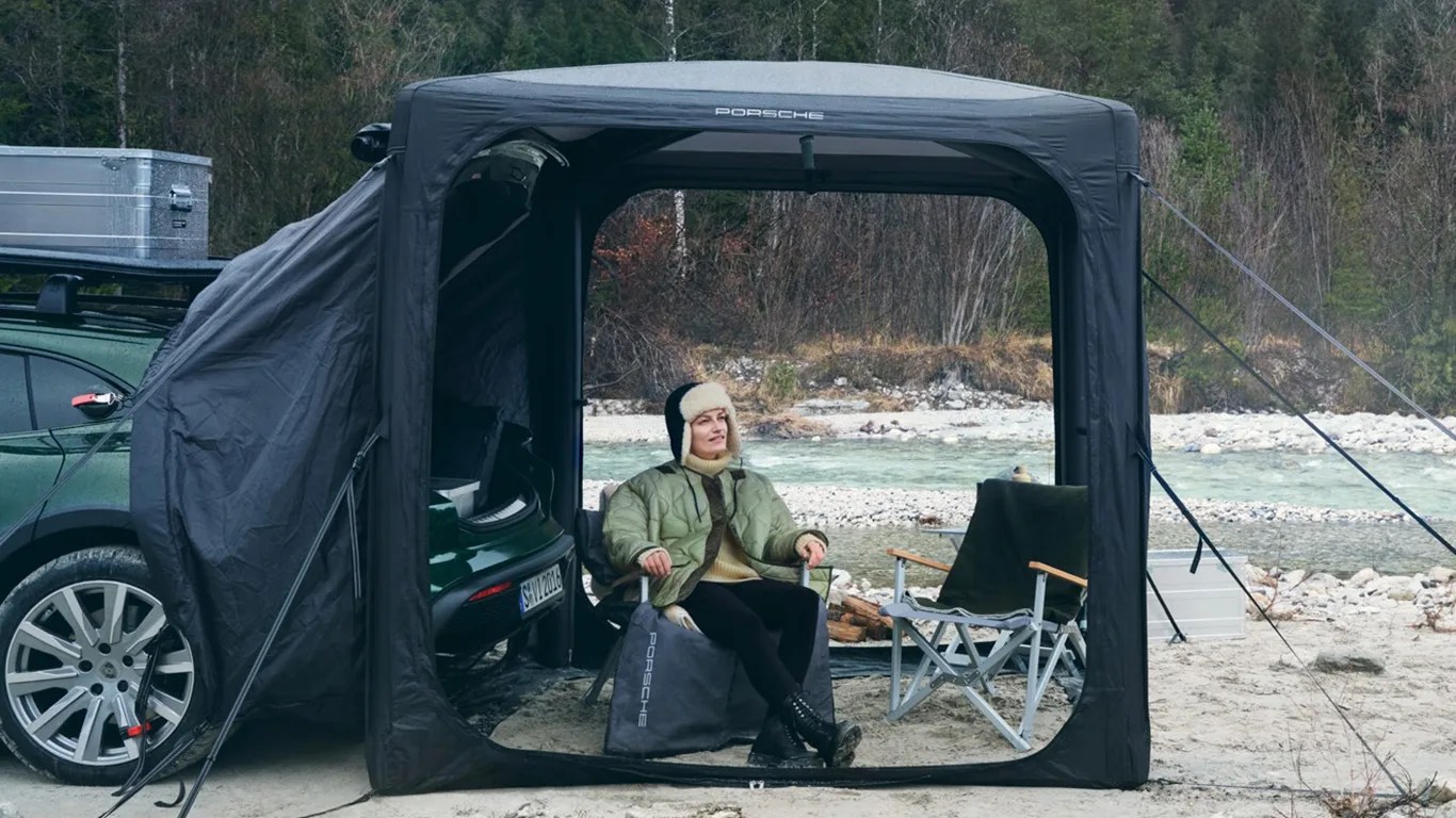 a woman sits inside a porsche tent connected to the back of a porsche car