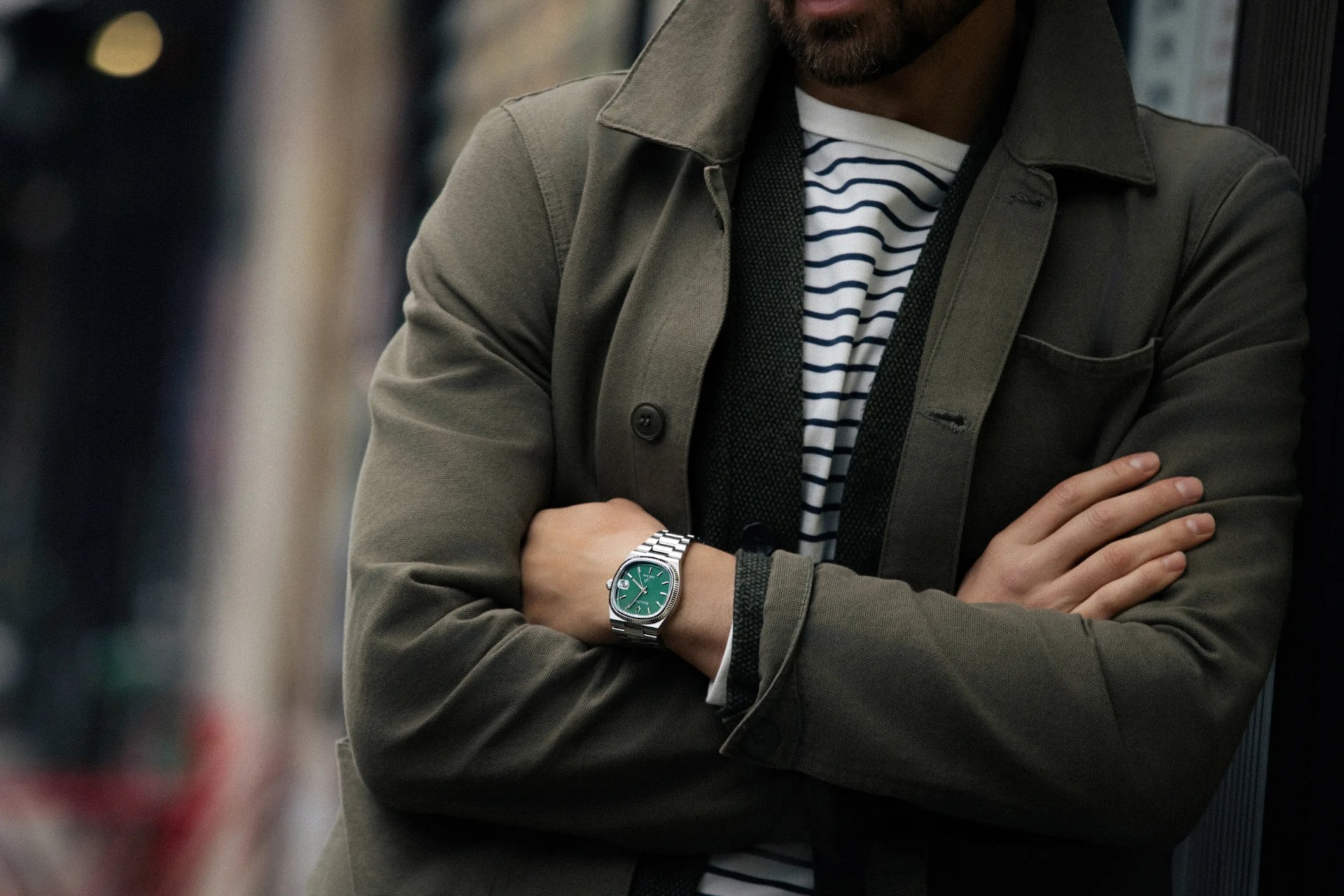 A man in a pea coat wears a Bulova Super Seville watch in stainless steel and green
