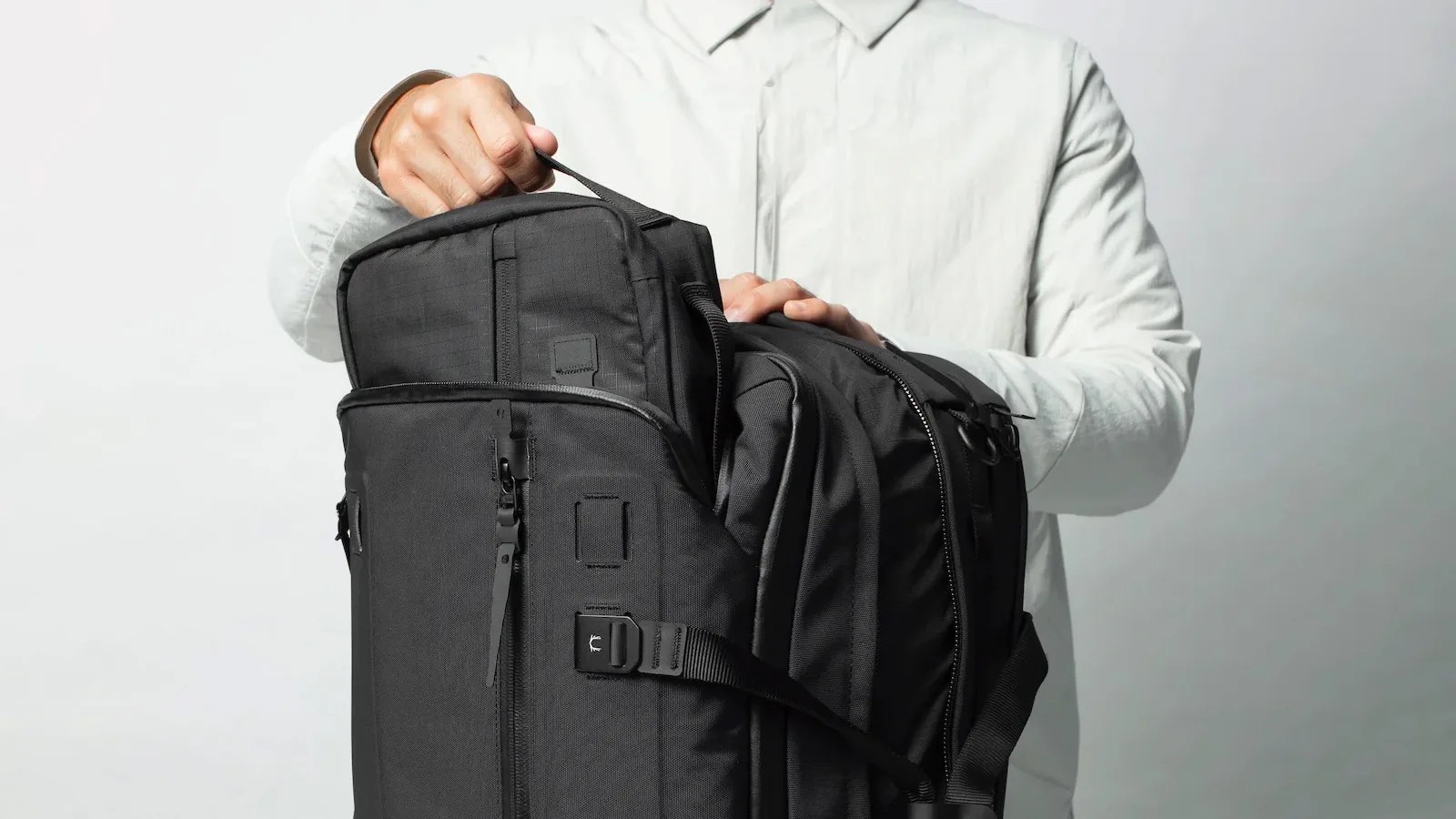 Black Ember Forge 40 Backpack being up packed by a mail in a white button up shirt